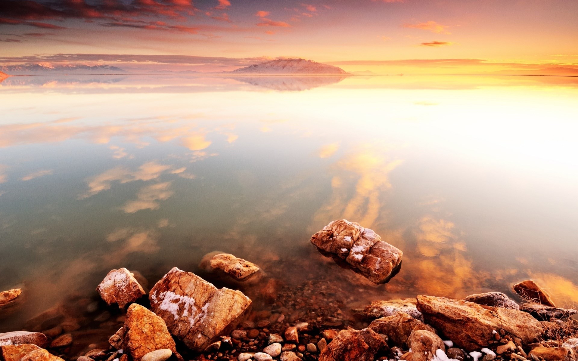 Sunset over a calm lake with rocky shore HD Wallpaper