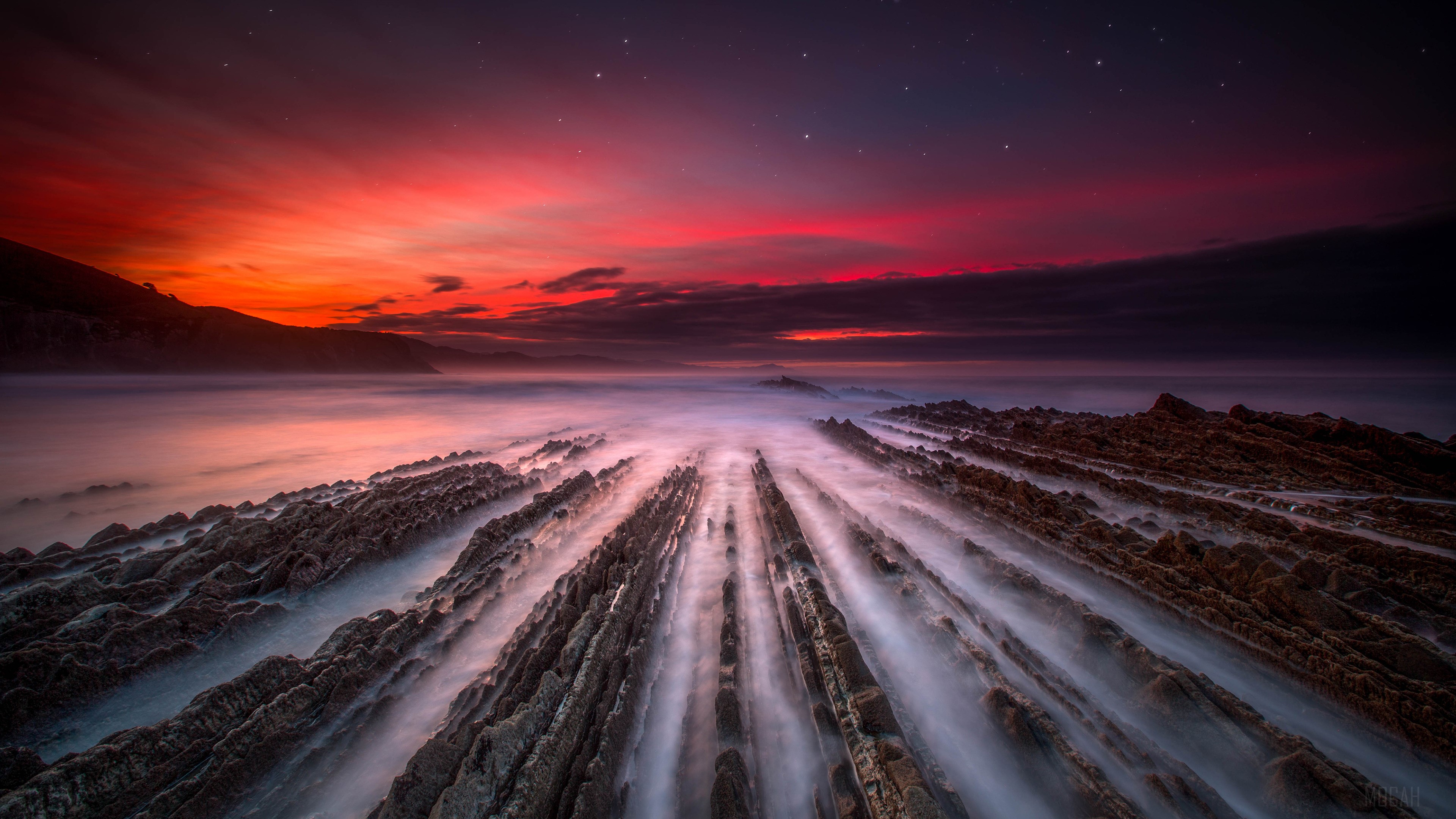 Sea sunset over rocky shore with mist HD Wallpaper