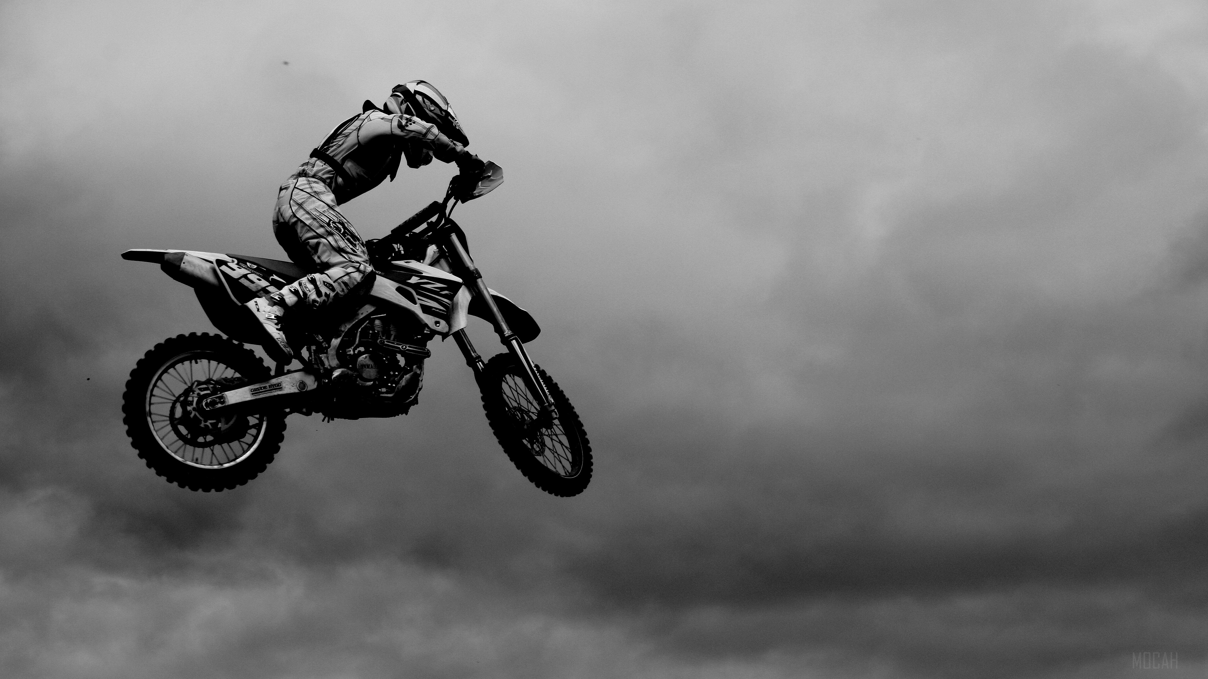 Motocross rider jumping against cloudy sky HD Wallpaper