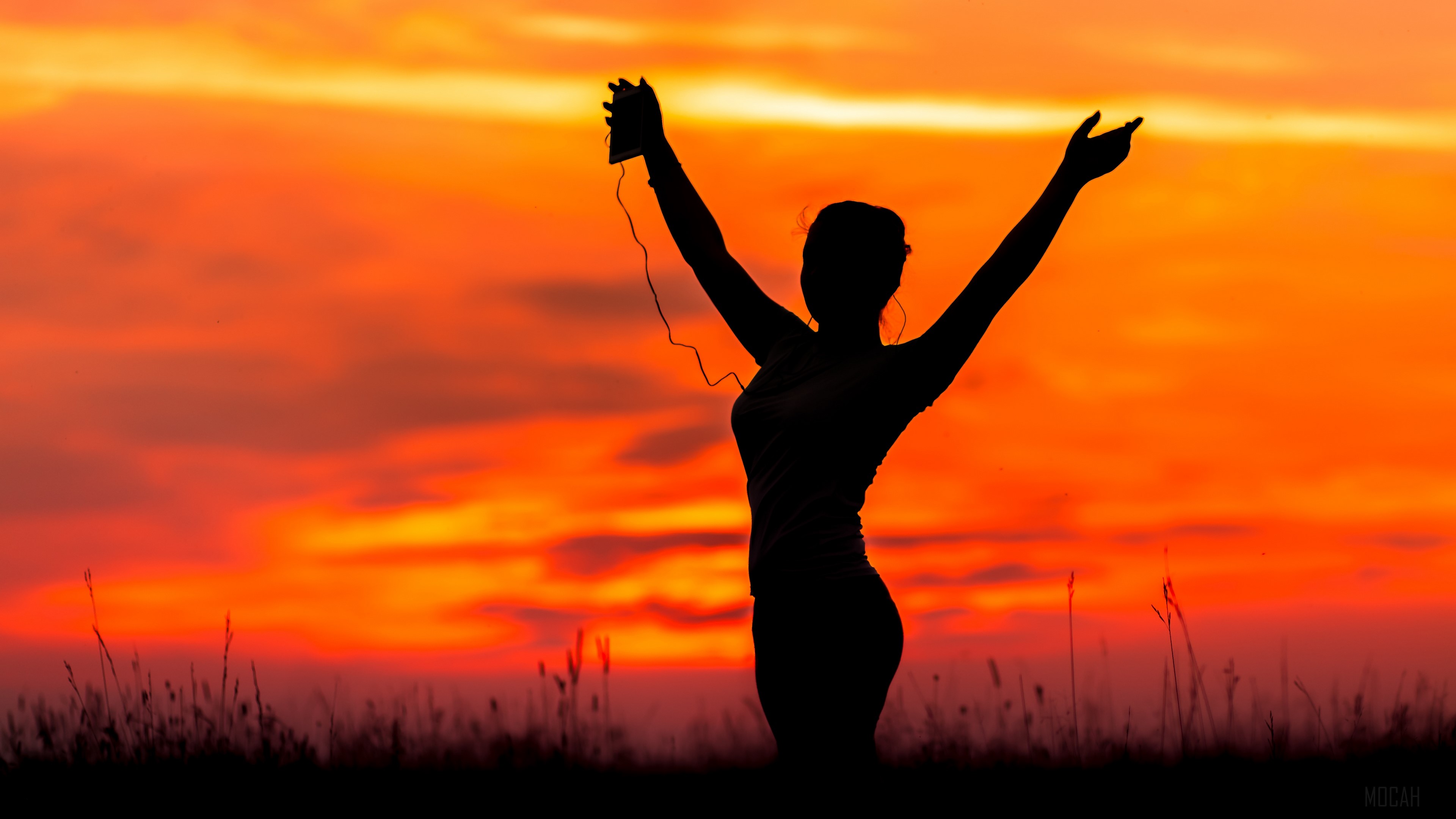 Silhouette of a person with arms raised at sunset HD Wallpaper