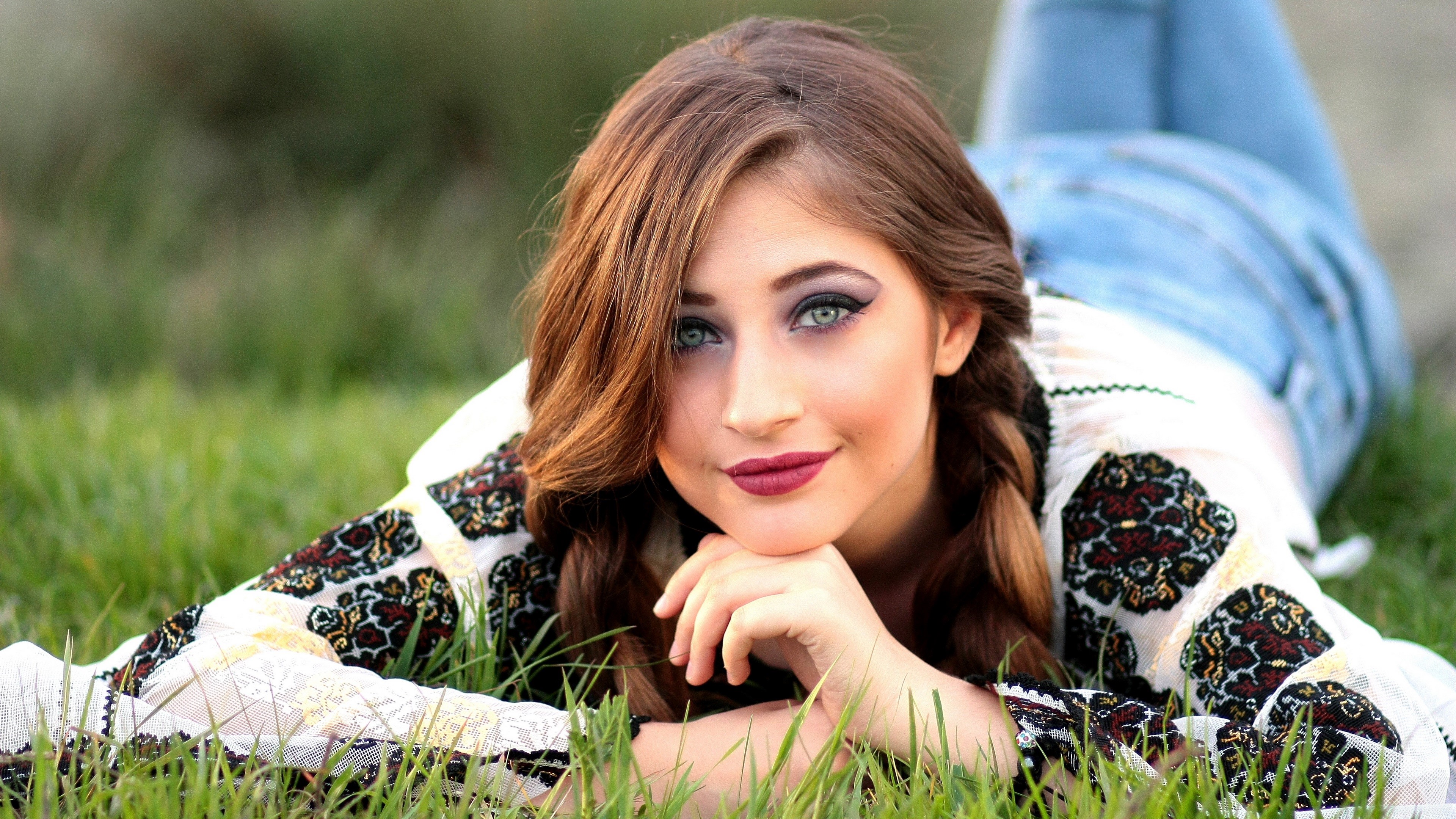 Woman with long hair lying in grass wearing embroidered shirt HD Wallpaper