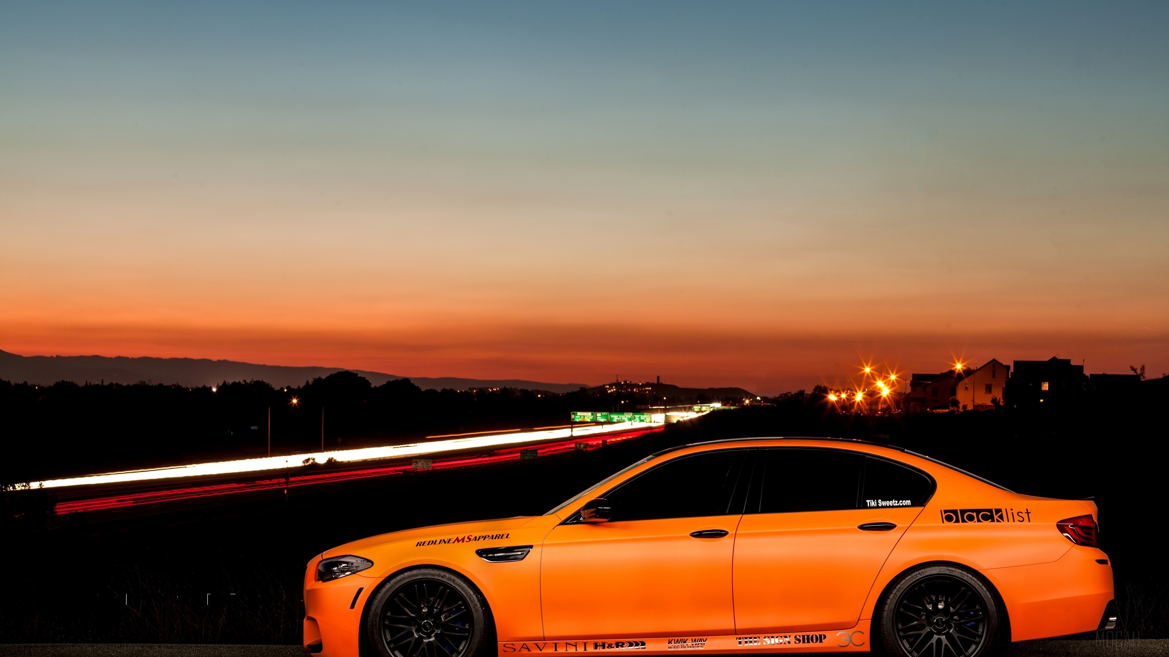 Orange BMW M5 with Blacklist sticker on highway at sunset HD Wallpaper