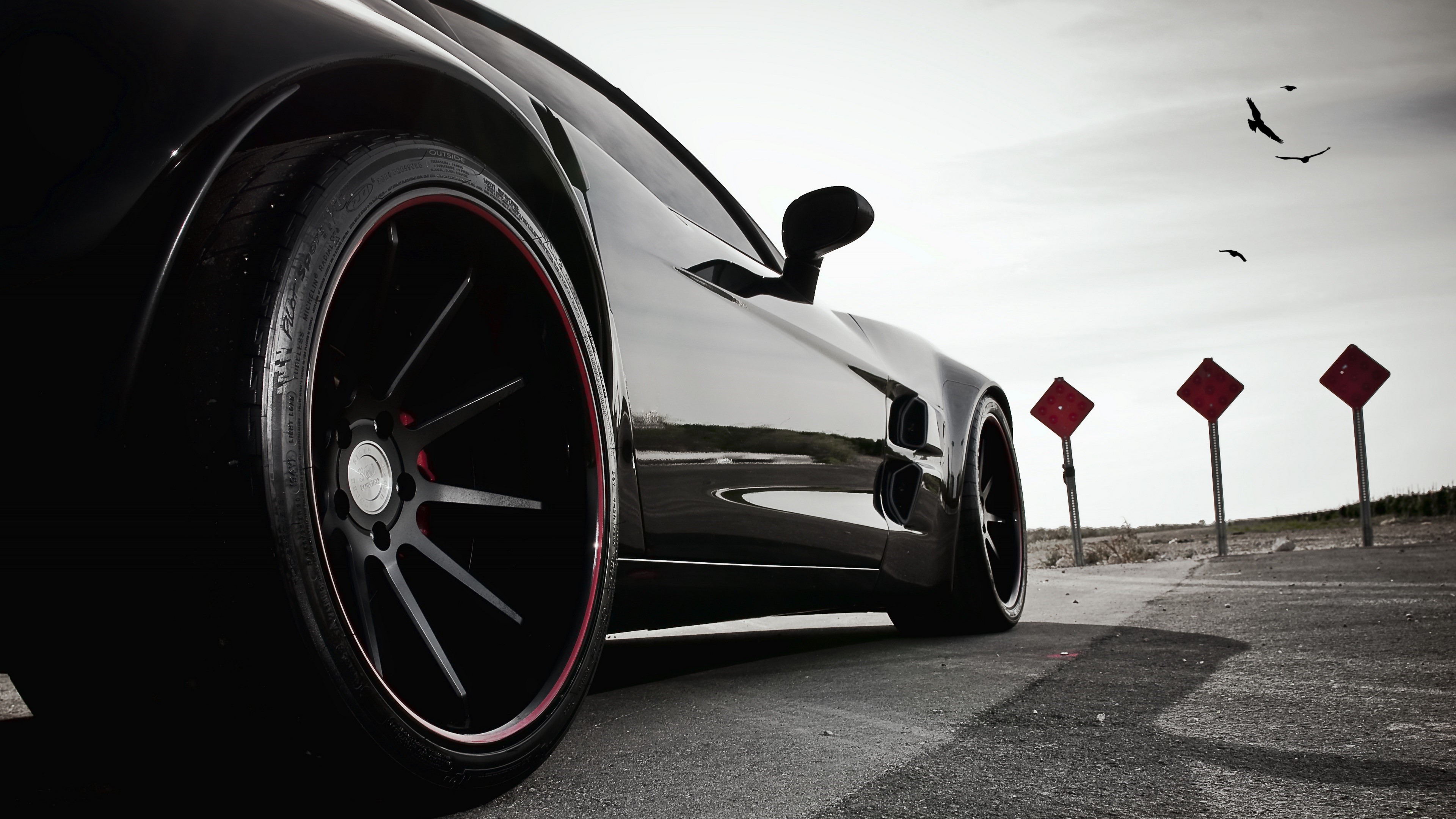 Black sports car on a road with red signs HD Wallpaper