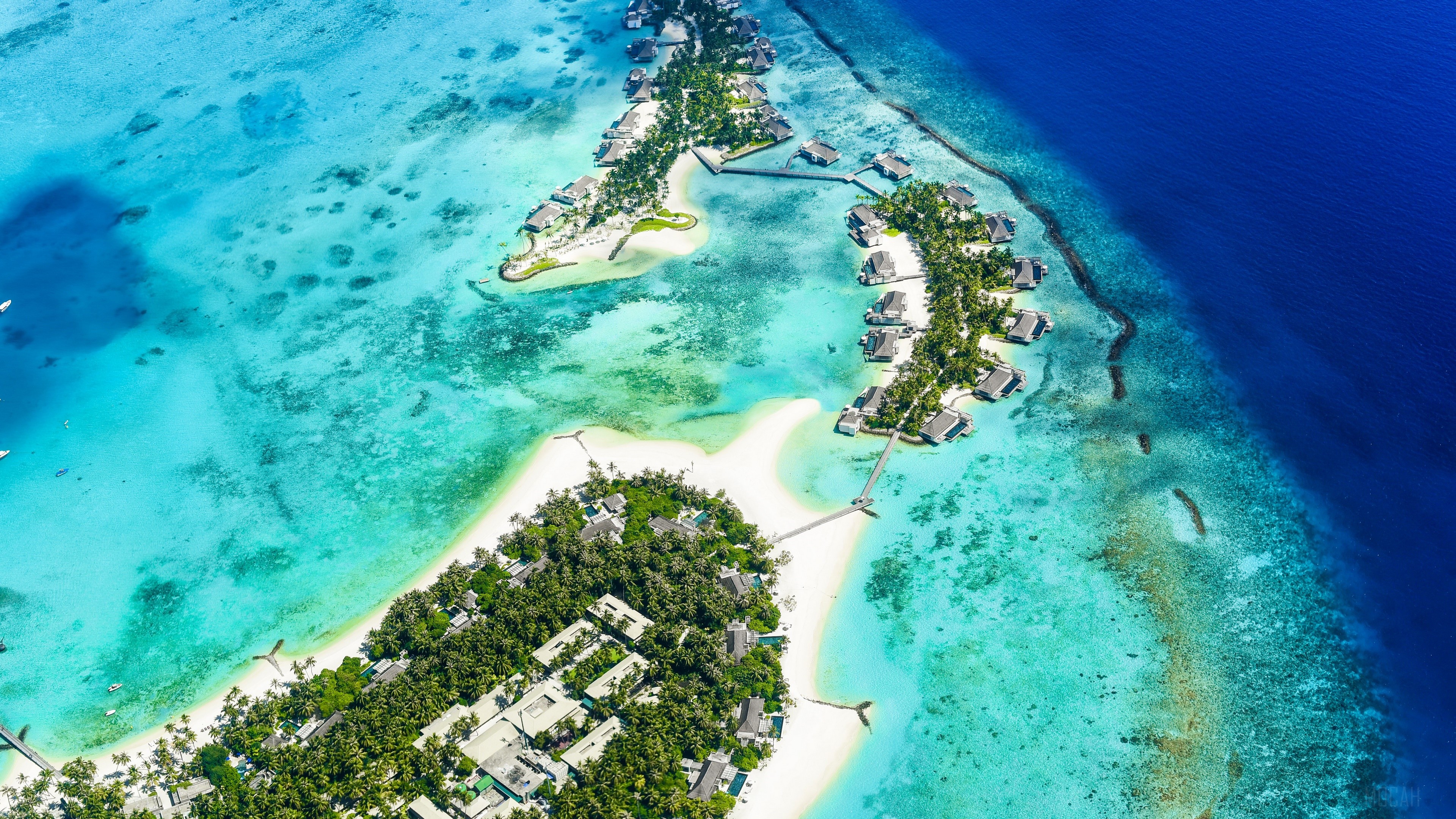 Aerial view of a tropical island resort with overwater bungalows HD Wallpaper