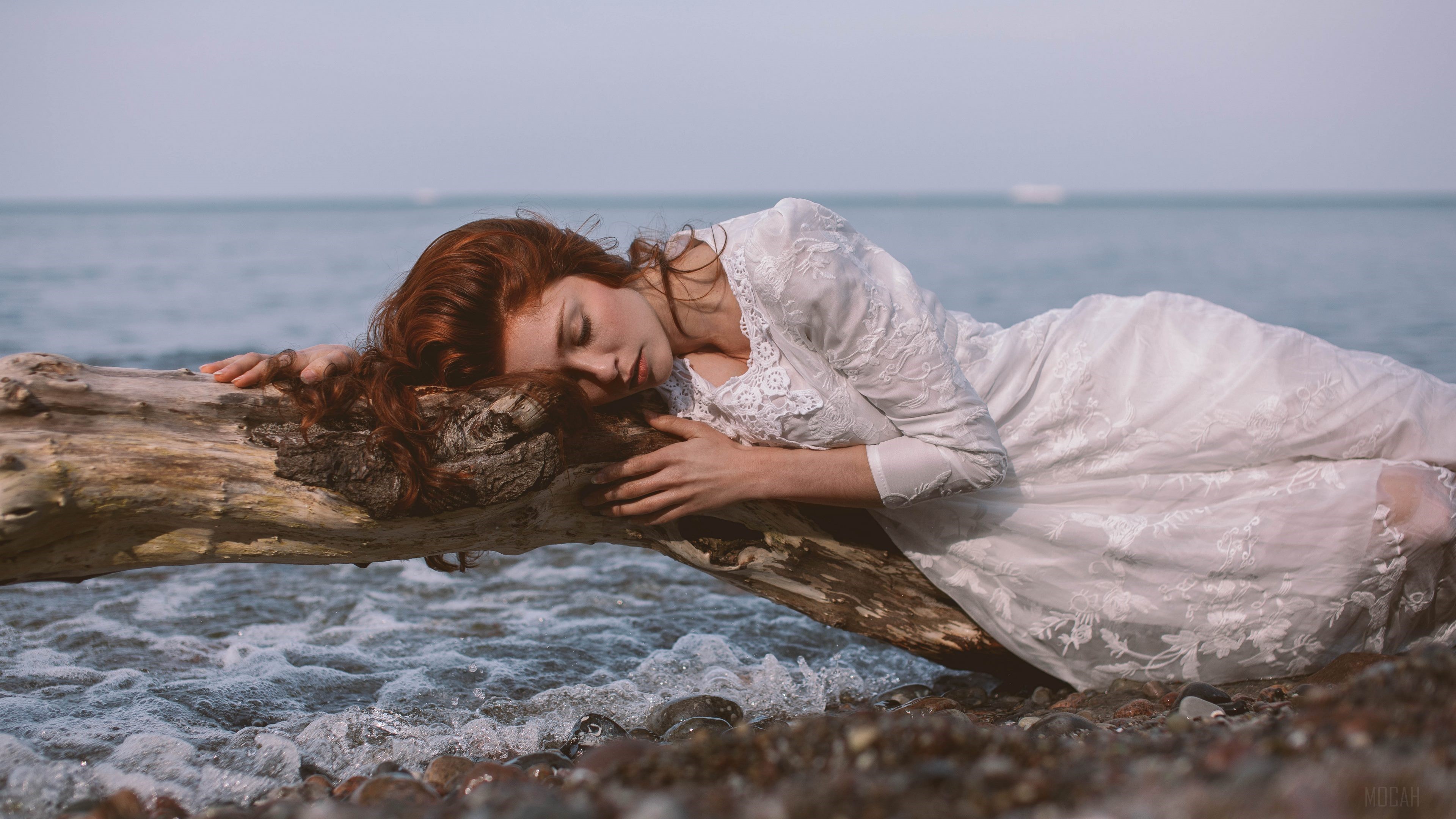 Redhead woman in white dress sleeping on a log by the sea 4K HD Wallpaper