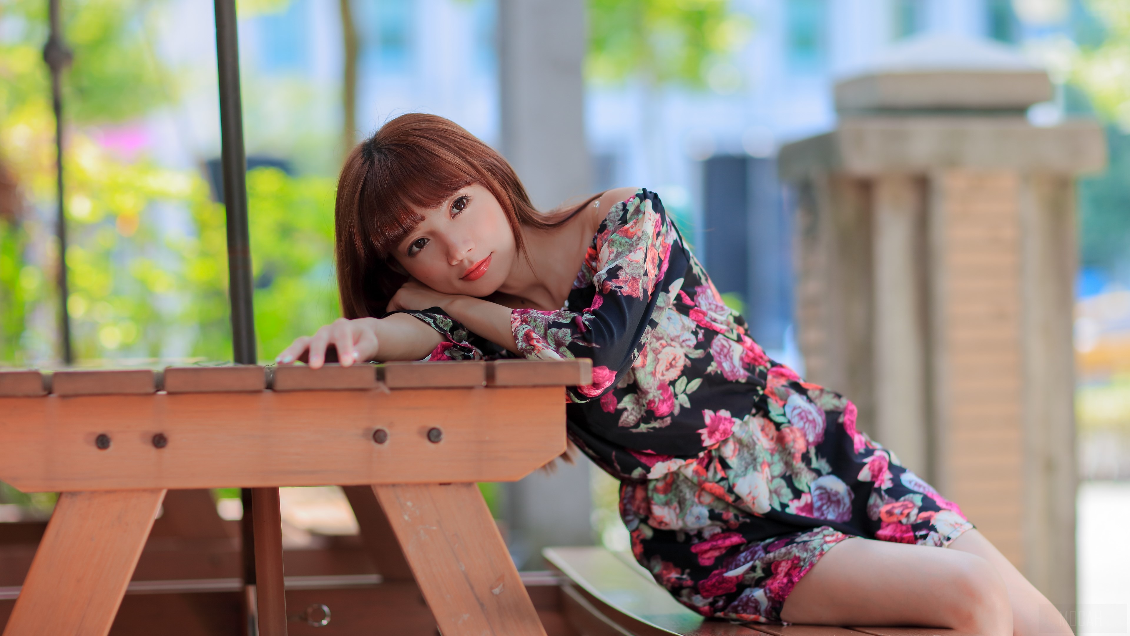 Woman in floral dress resting on a picnic table HD Wallpaper