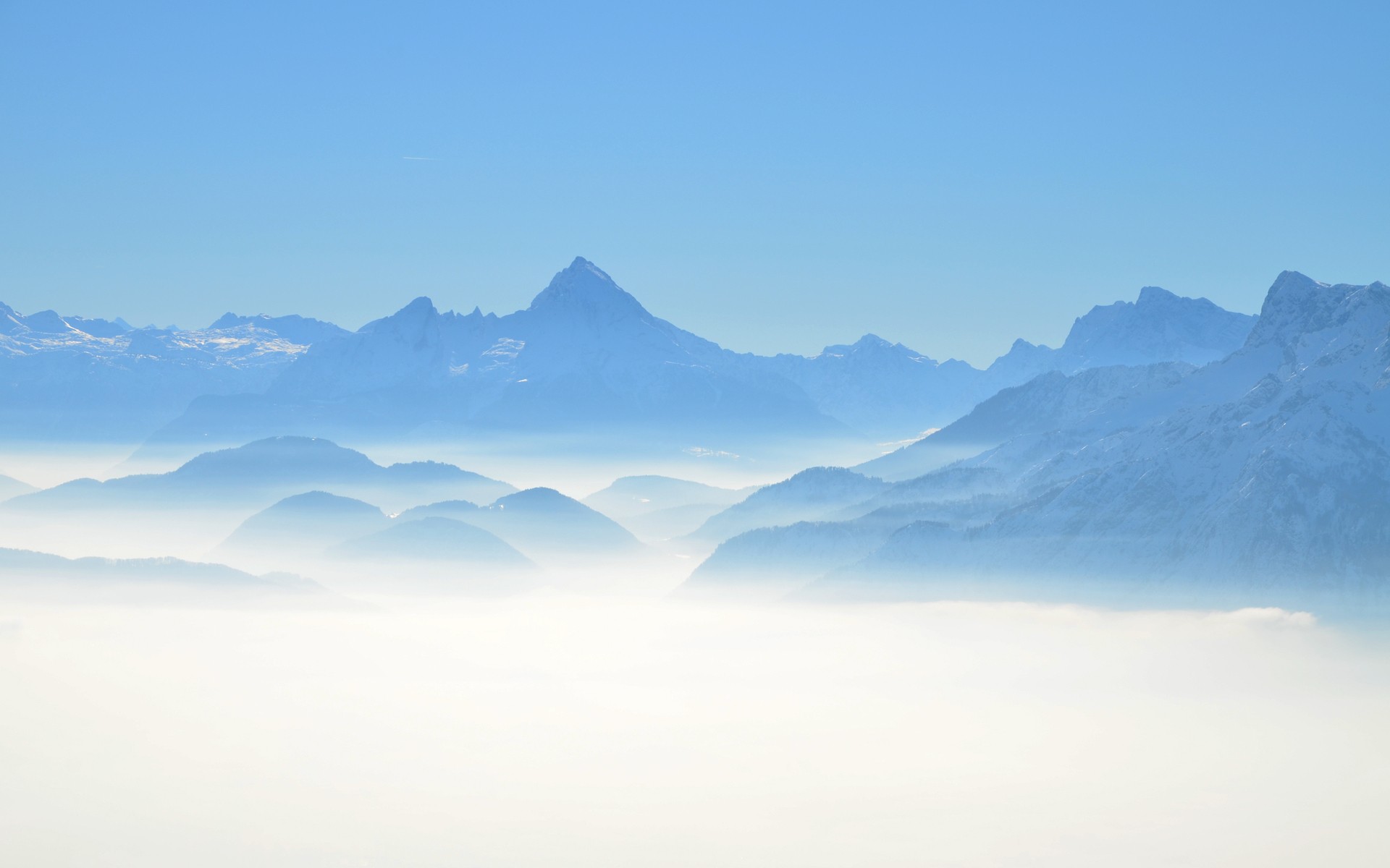 Misty mountains under a clear blue sky HD Wallpaper
