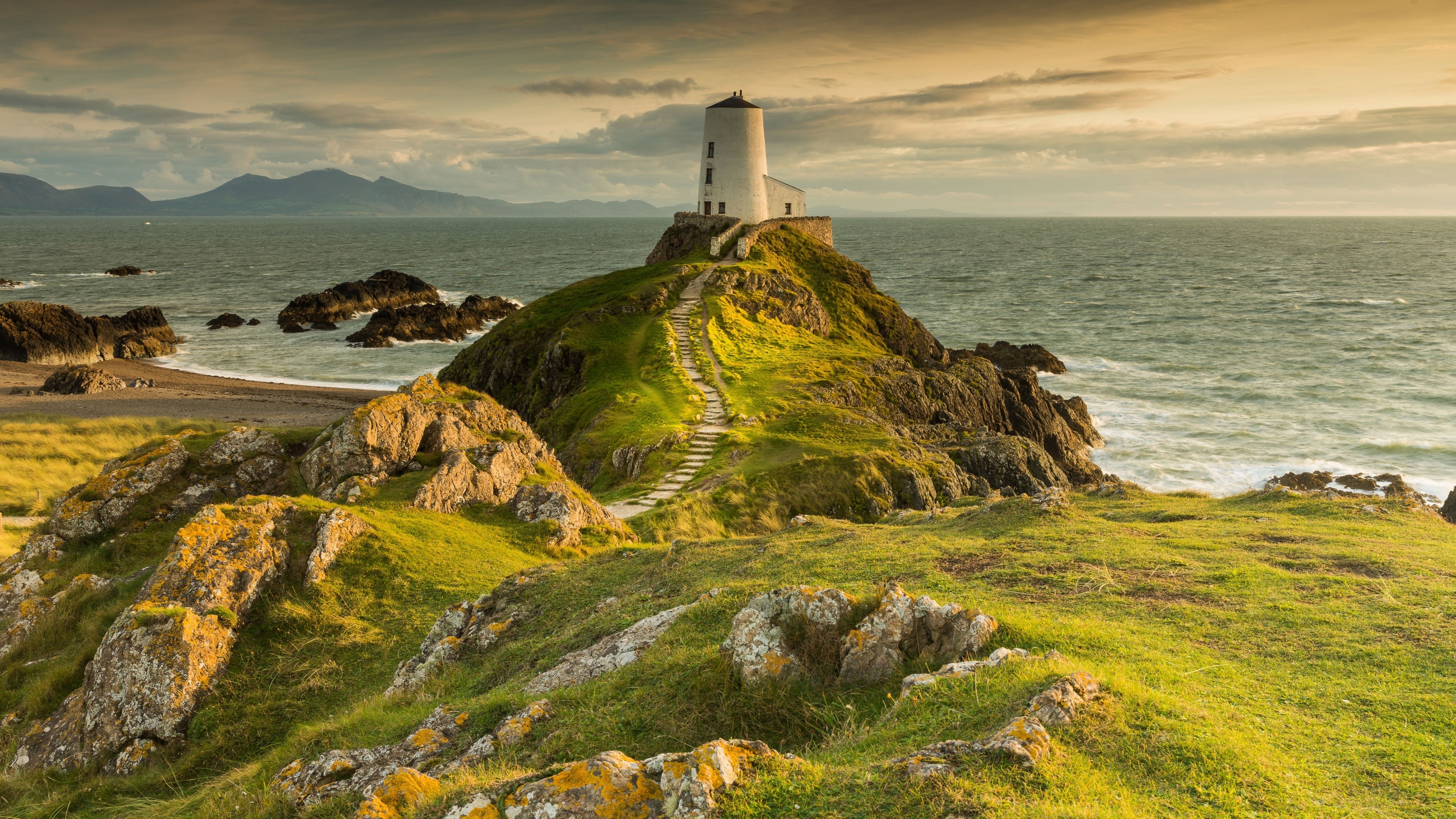 Lighthouse on a rocky hill overlooking the ocean HD Wallpaper