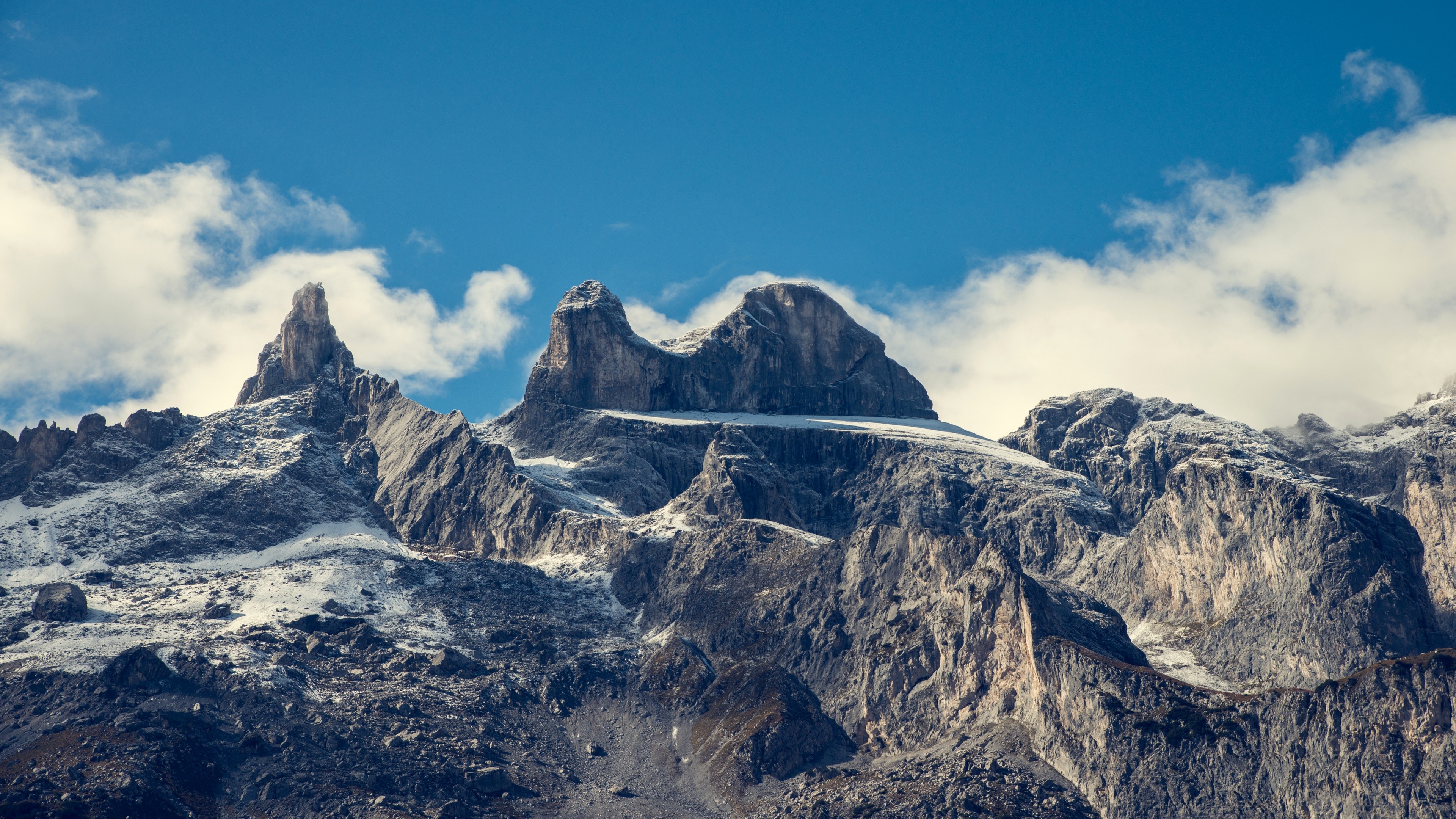 Mountain peaks under a blue sky with clouds HD Wallpaper