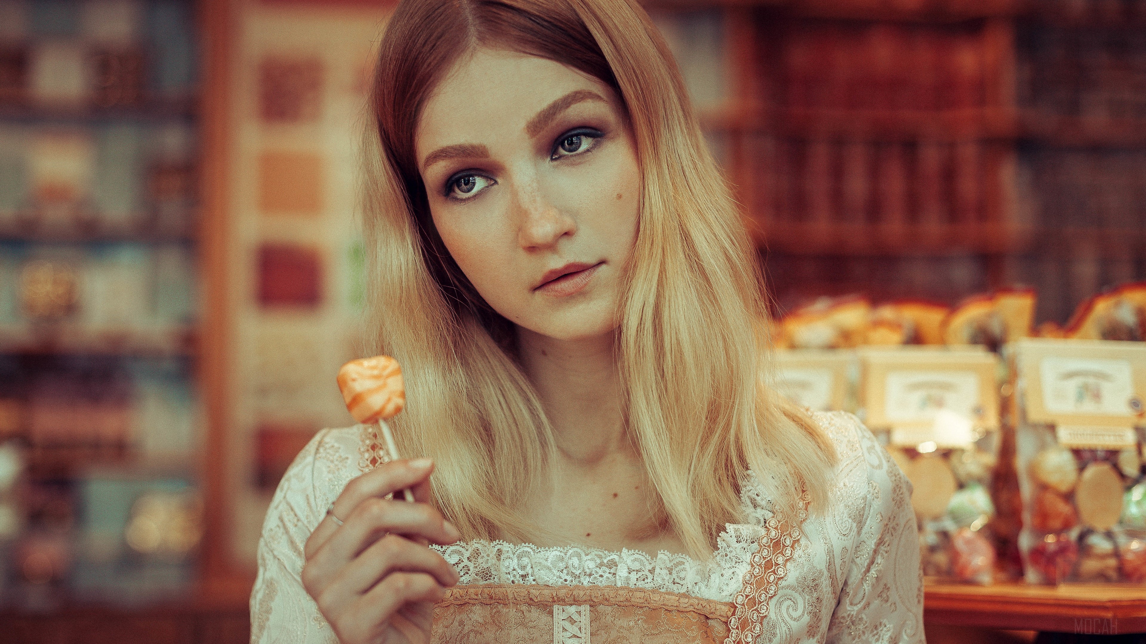 Blonde woman holding candy pop in candy store 4K HD Wallpaper
