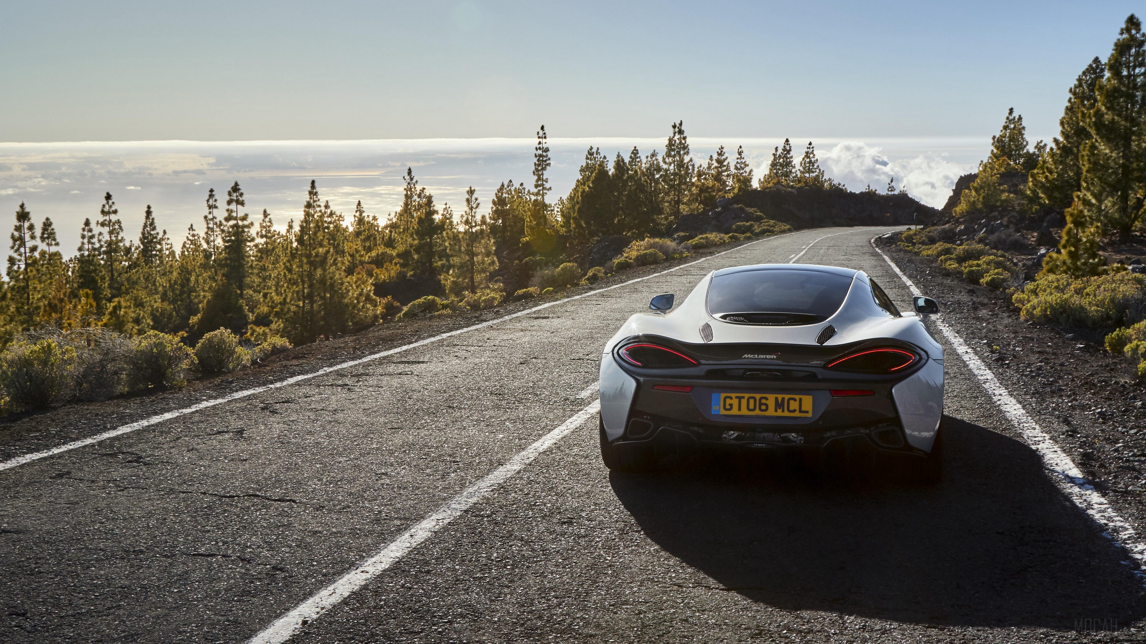 White McLaren 570GT driving on a mountain road HD Wallpaper