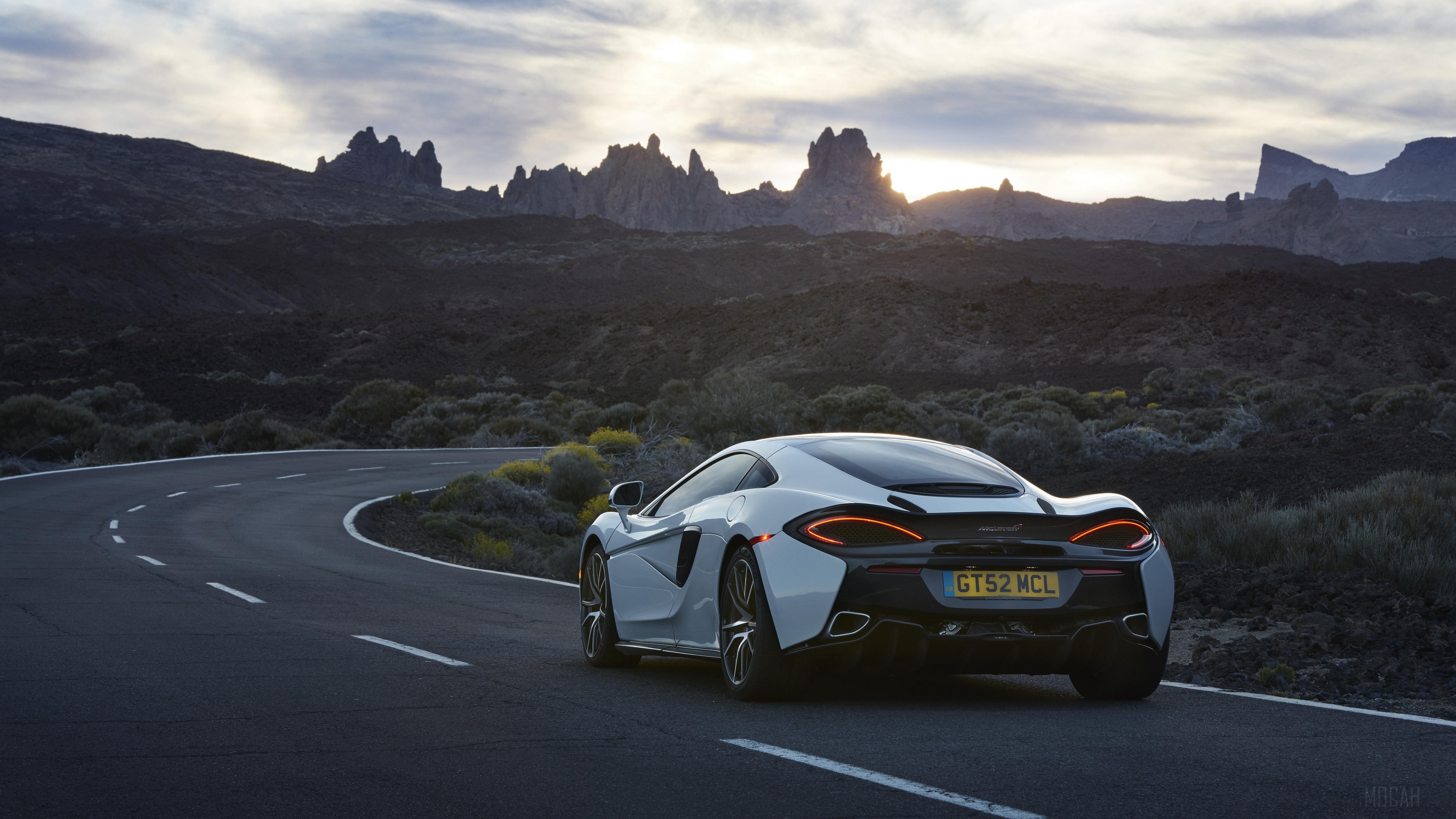White McLaren 570GT driving on a winding road HD Wallpaper