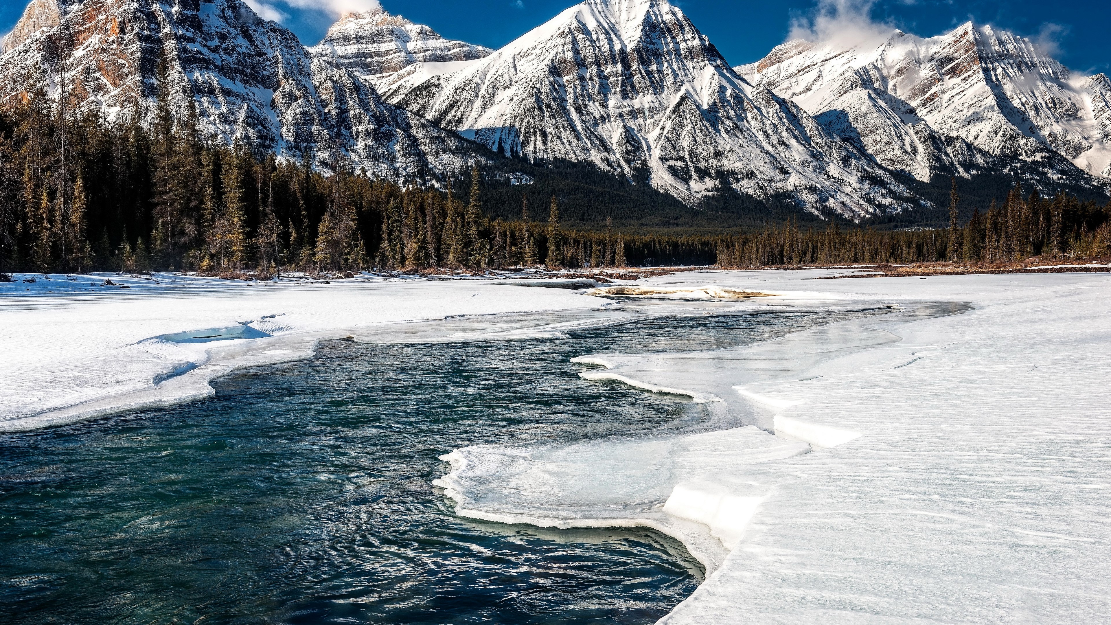 Snow-covered mountains and a partially frozen river in Alberta, Canada 4K HD Wallpaper