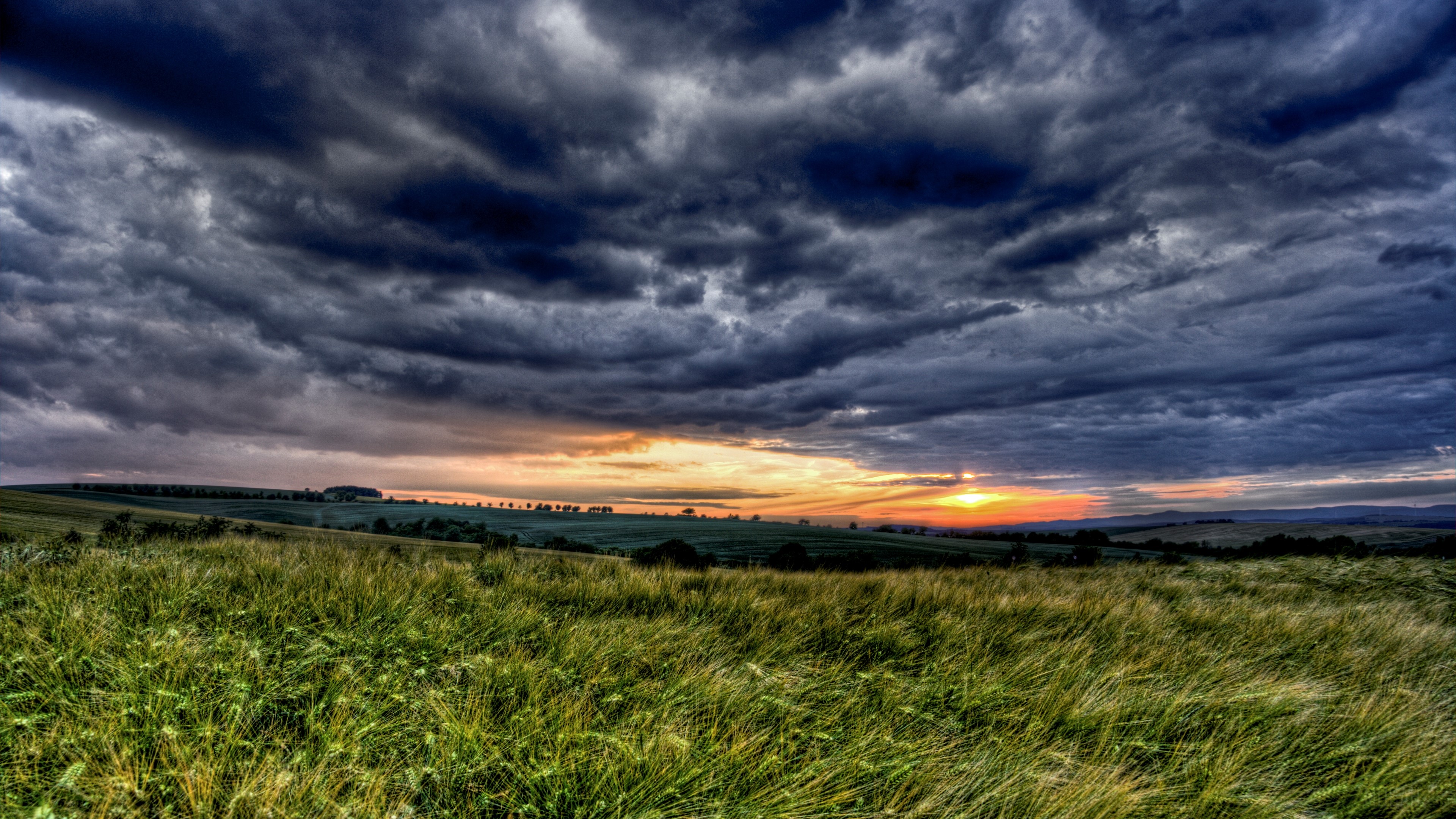 Stormy Sunset Over Grassy Hills HD Wallpaper