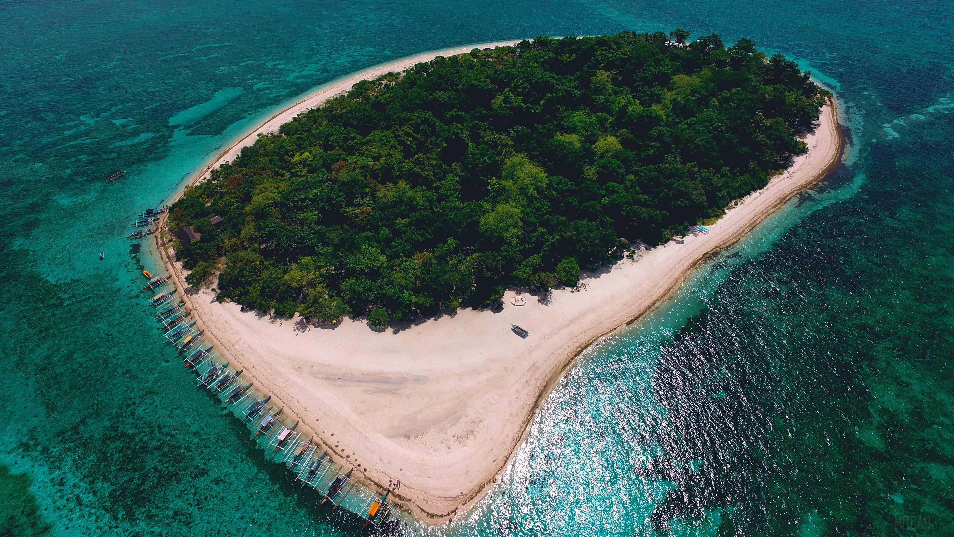 Island with lush trees and boats in turquoise ocean 4K HD Wallpaper