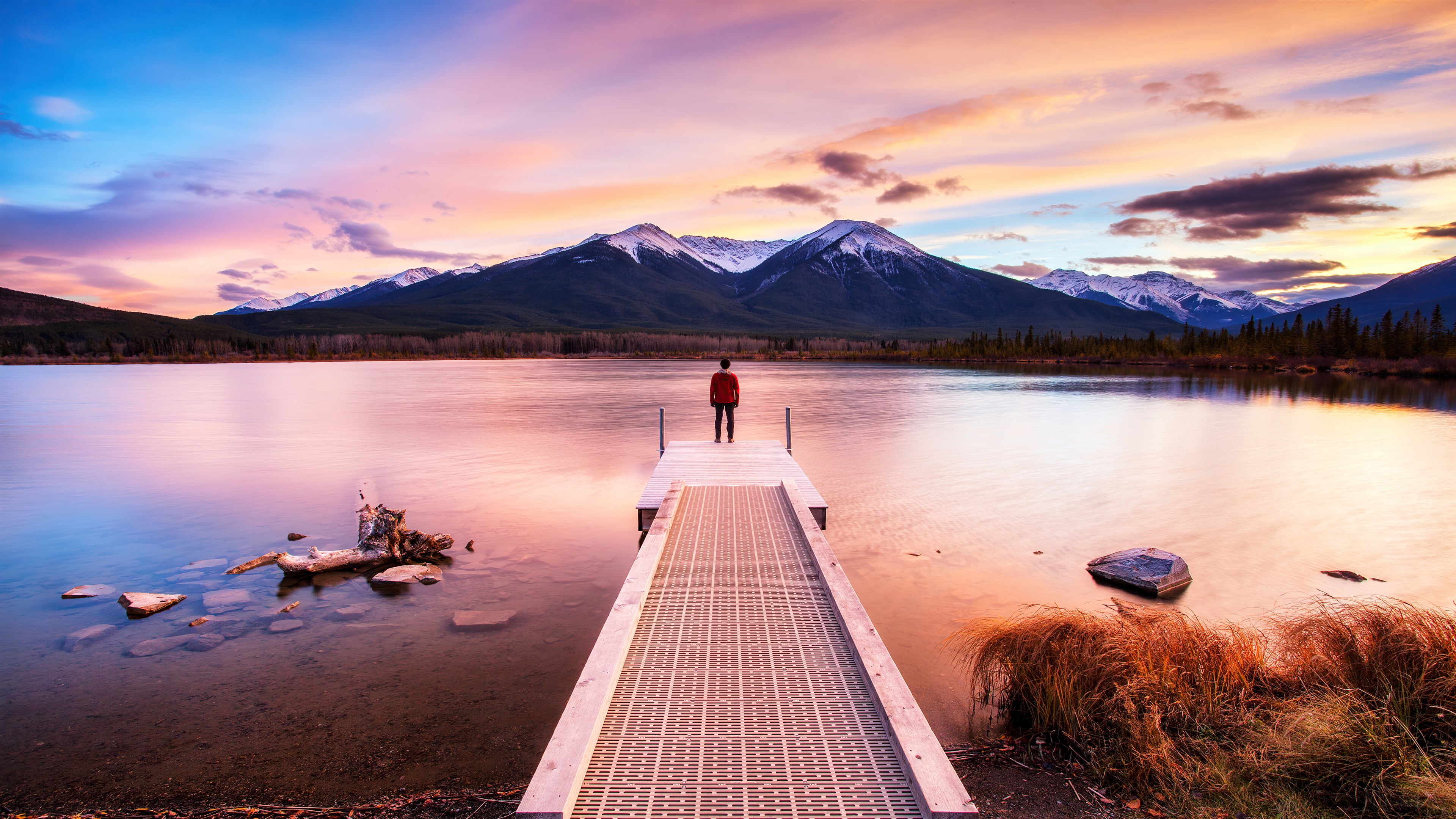Person Standing on Dock at Sunset with Mountains HD Wallpaper