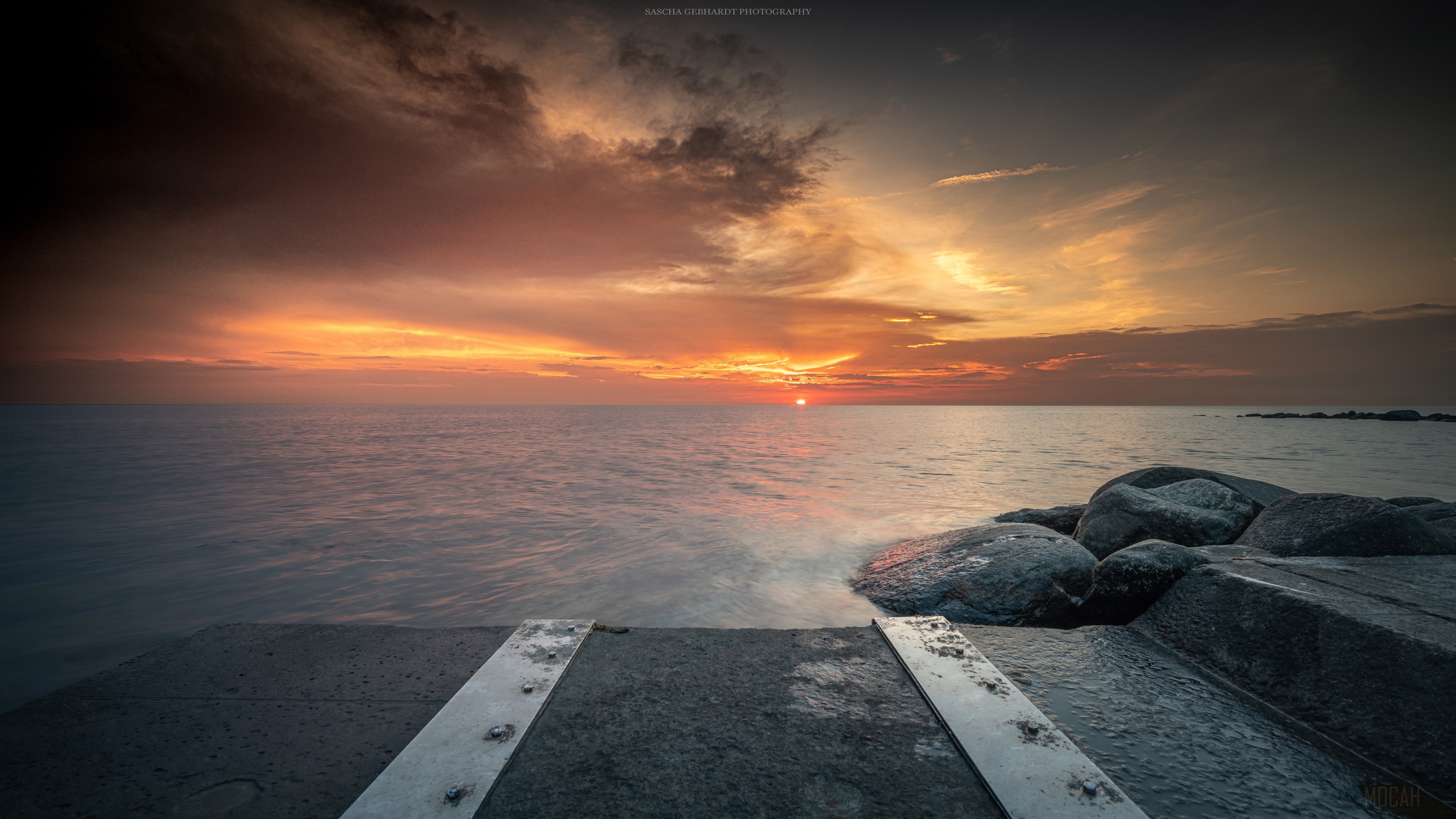 Sunset over the sea with rocks and pier HD Wallpaper