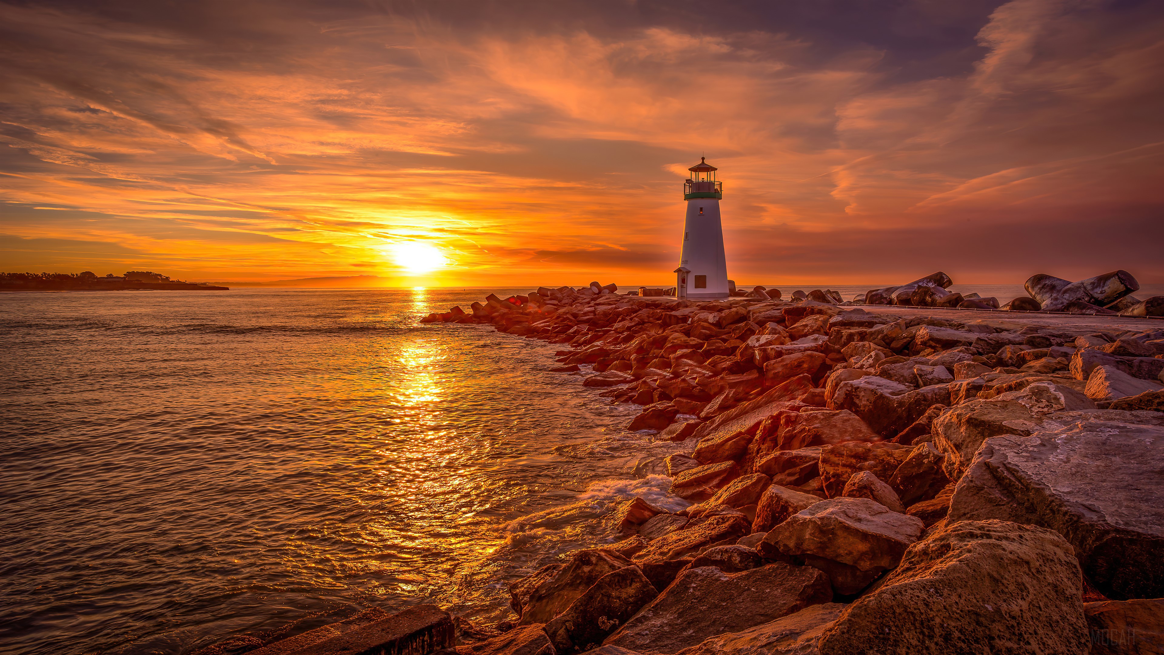 Lighthouse on rocky shore at sunset 4K HD Wallpaper
