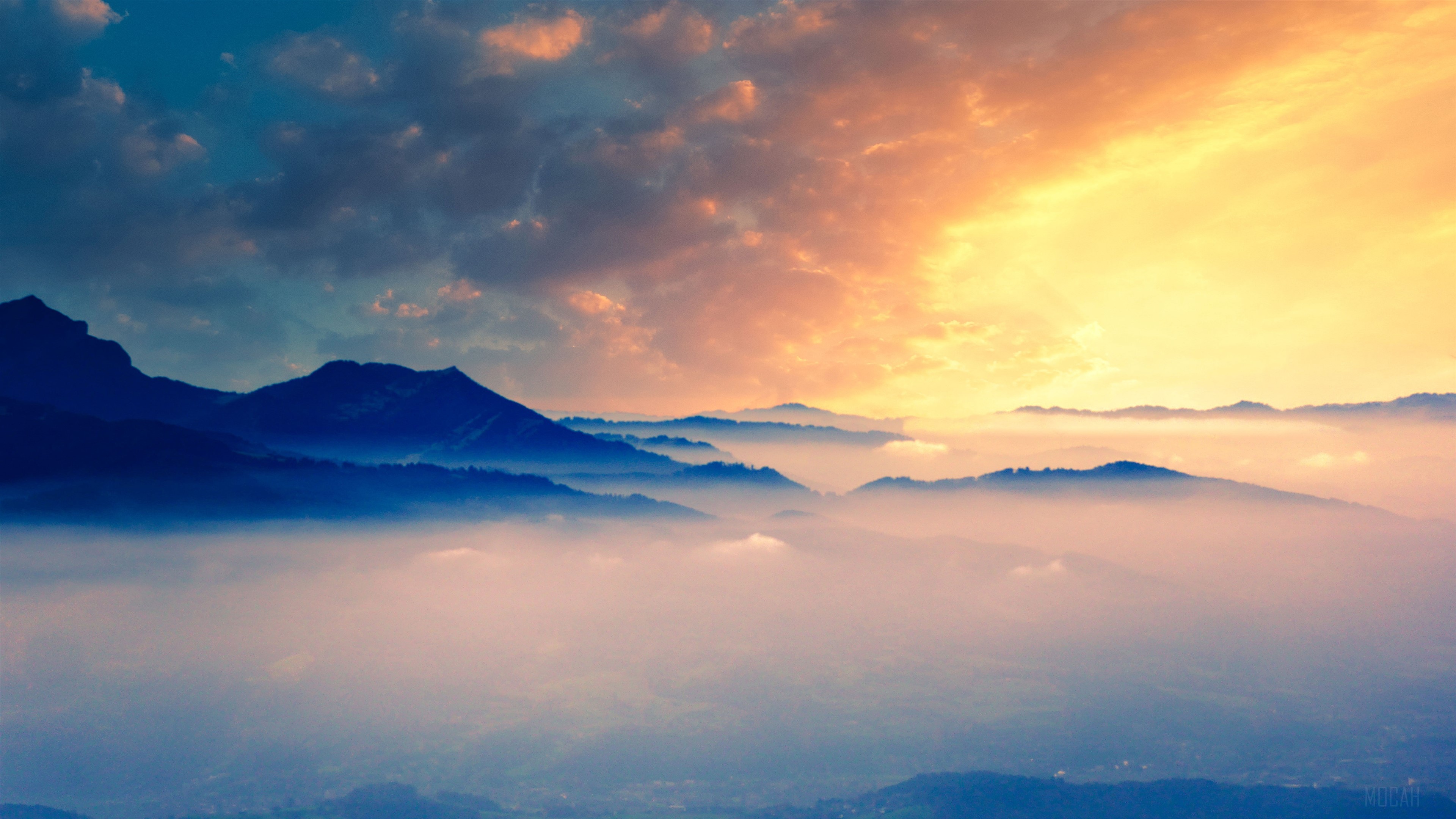 Mountains shrouded in fog at sunrise with dramatic clouds HD Wallpaper
