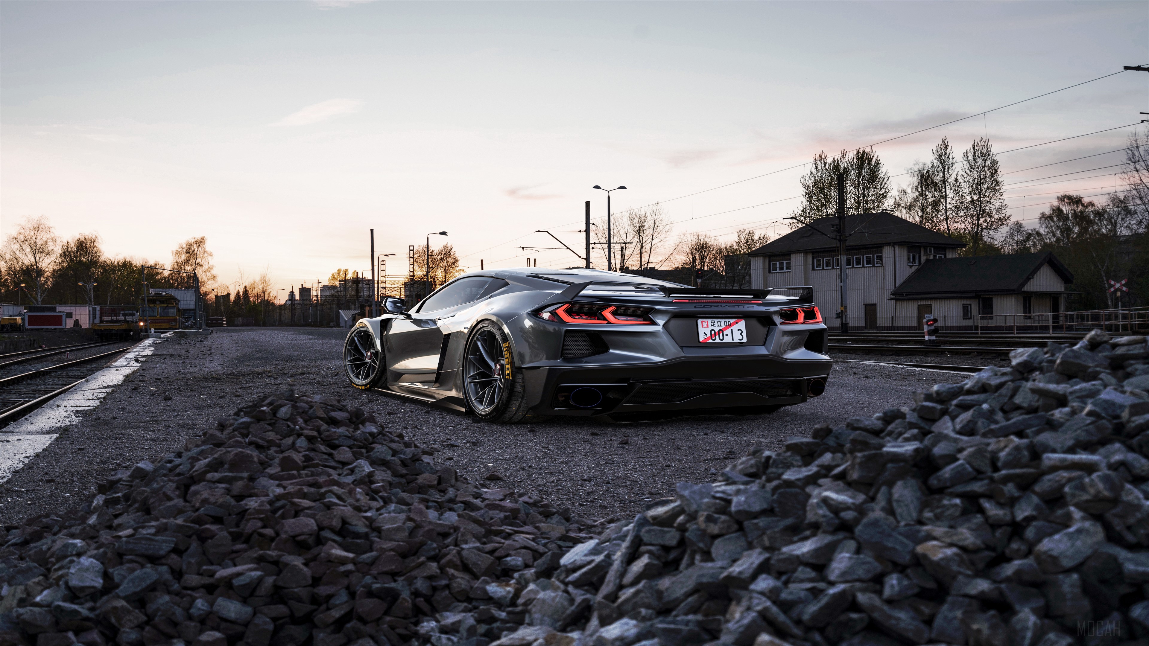 Gray Corvette C8 parked on gravel near train tracks HD Wallpaper