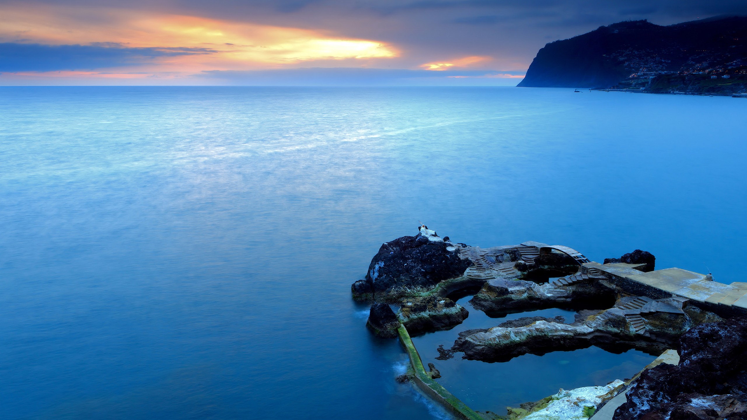Ocean sunset with rocky coastline and swimming pools HD Wallpaper