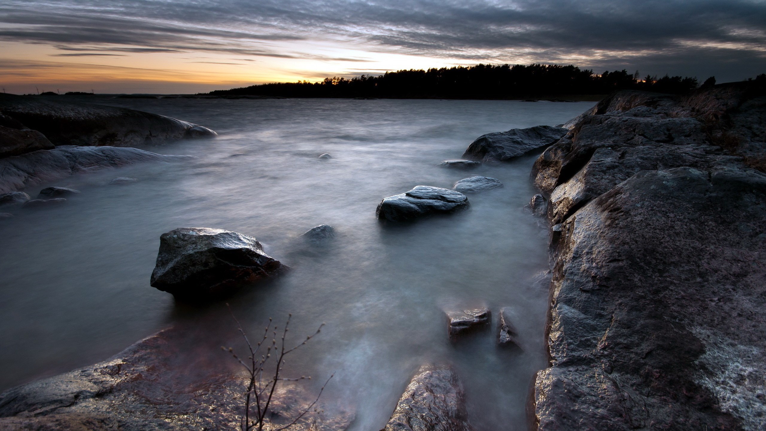 Rocky shoreline at dusk with calm water HD Wallpaper