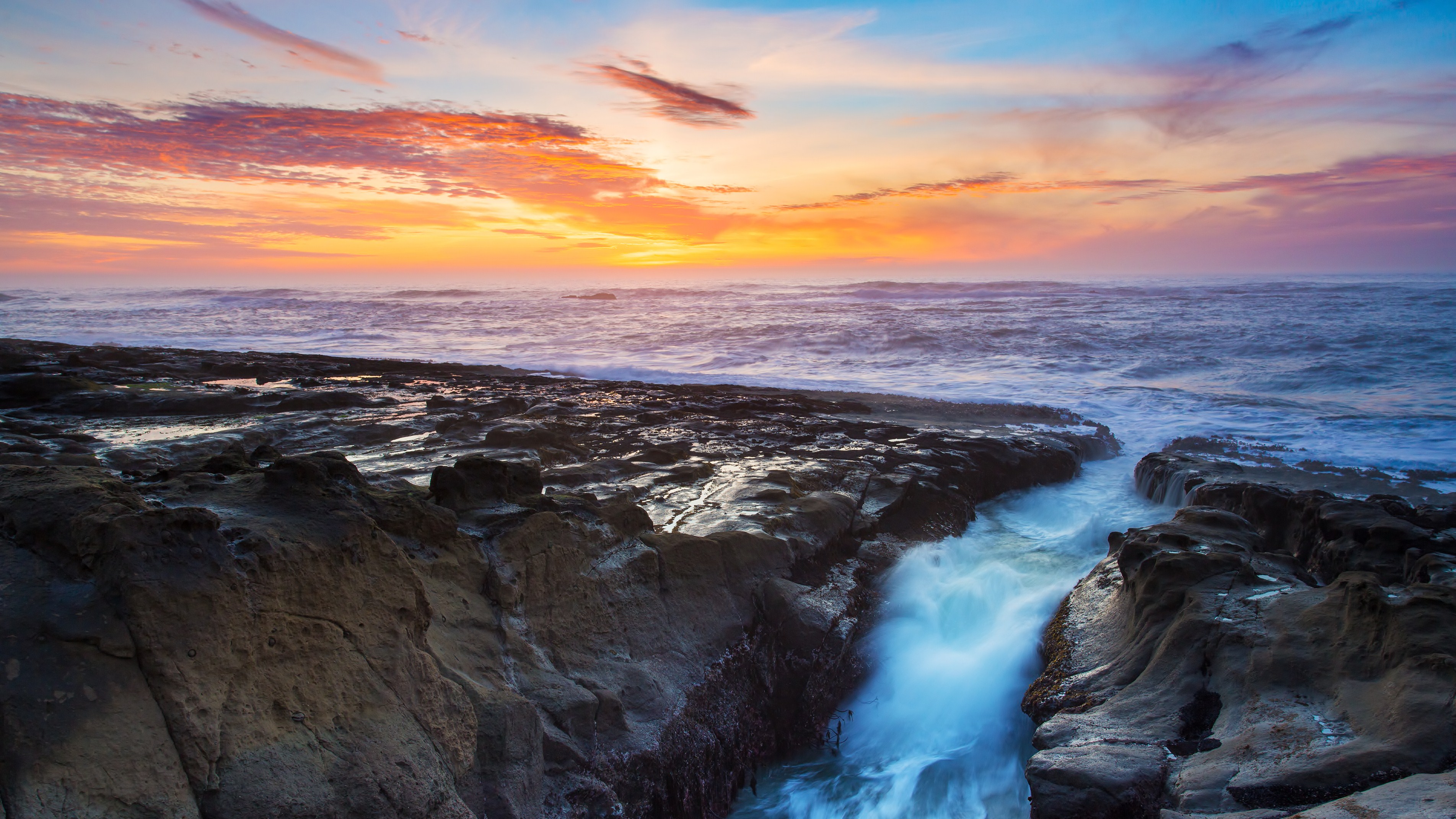 Ocean sunset over rocky coastline with crashing waves HD Wallpaper