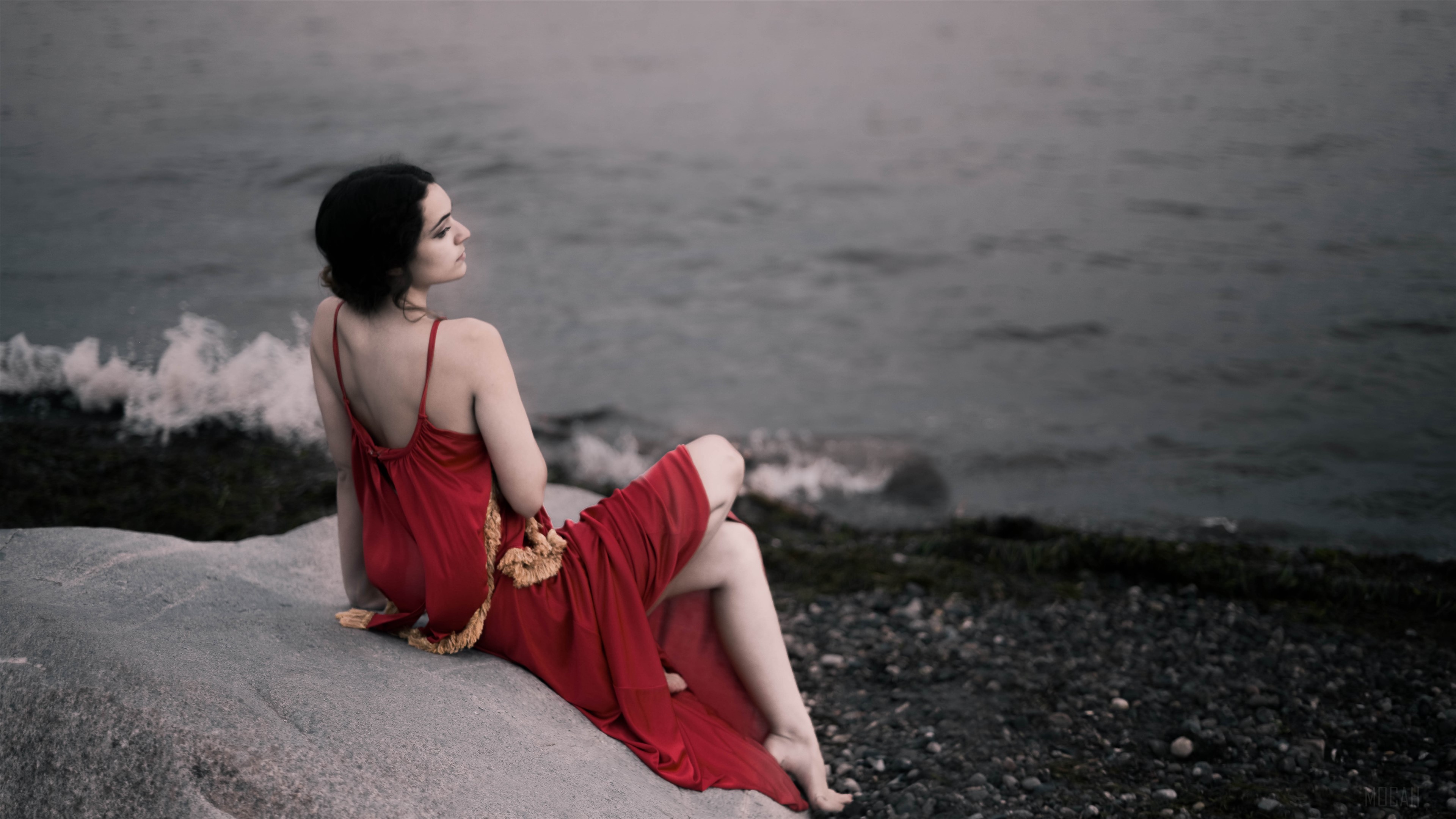 Girl in red dress sitting on rocks by the water 4K HD Wallpaper