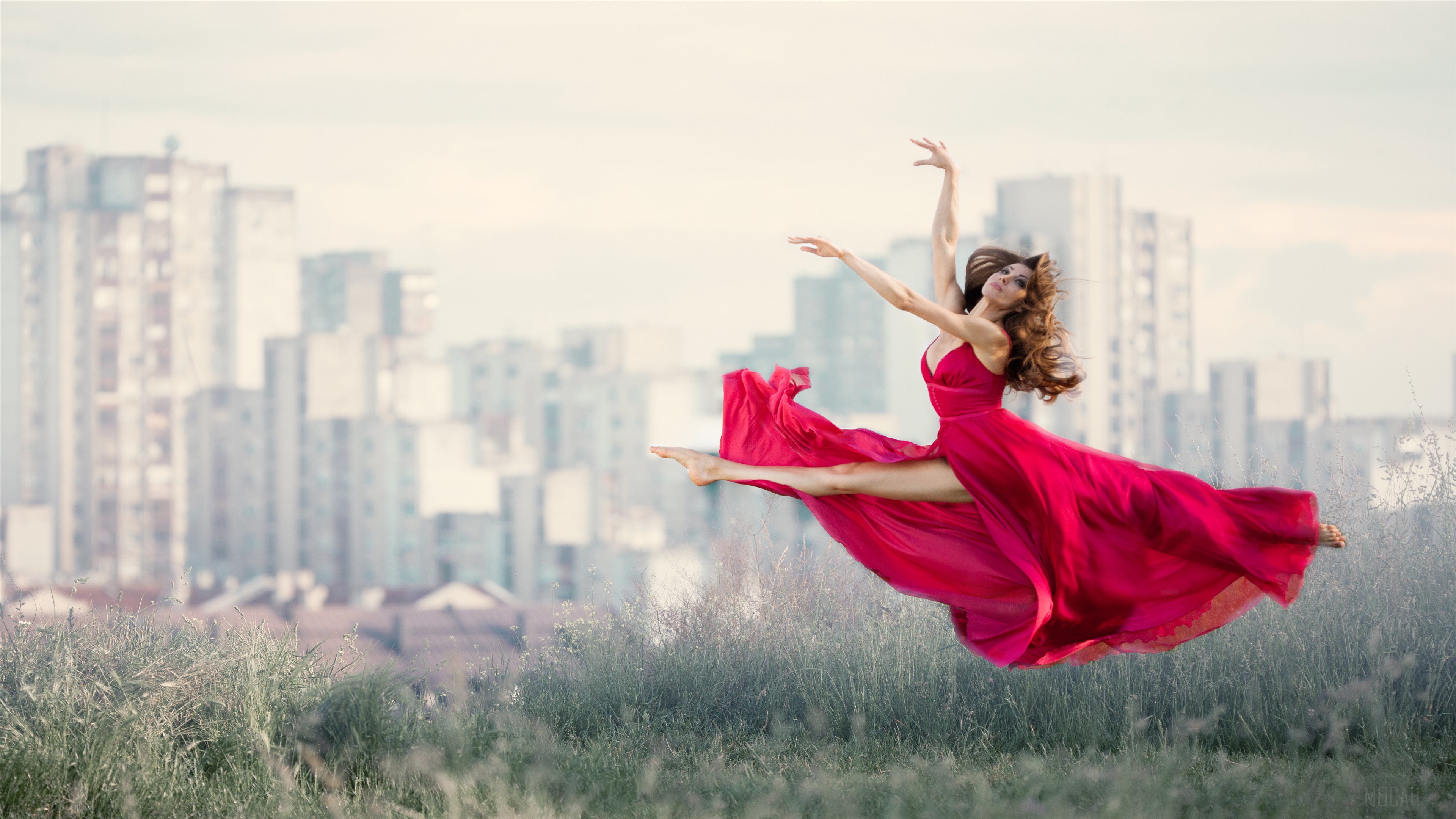 Woman in red dress dancing in front of city buildings HD Wallpaper