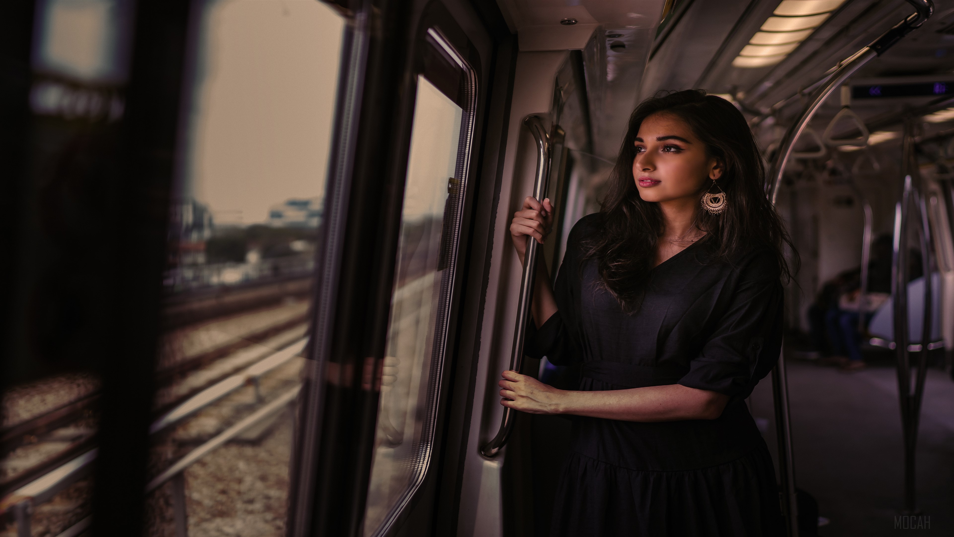 Woman in black dress on train looking out window HD Wallpaper
