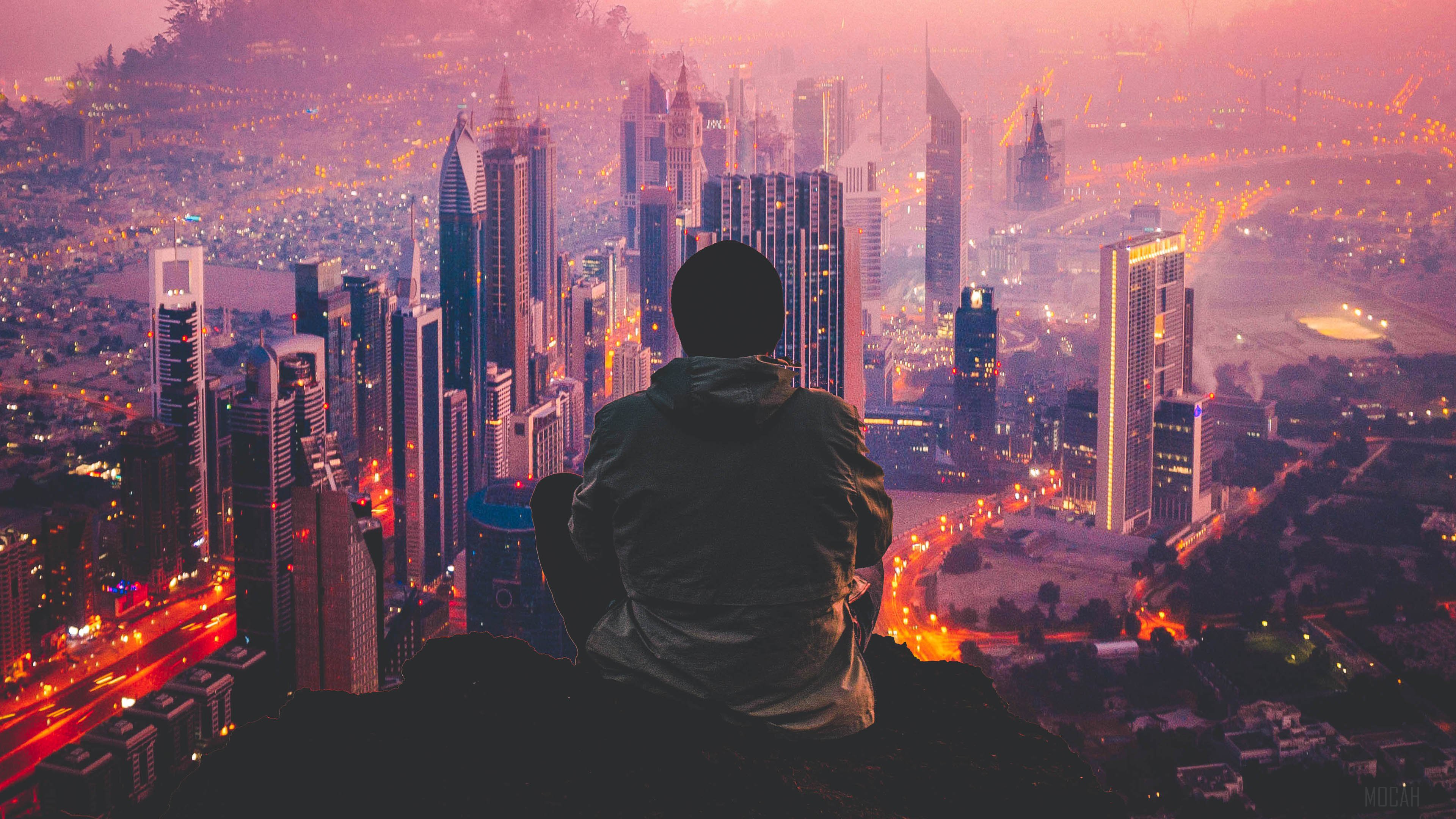 Man sitting on a cliff overlooking a city at dusk HD Wallpaper