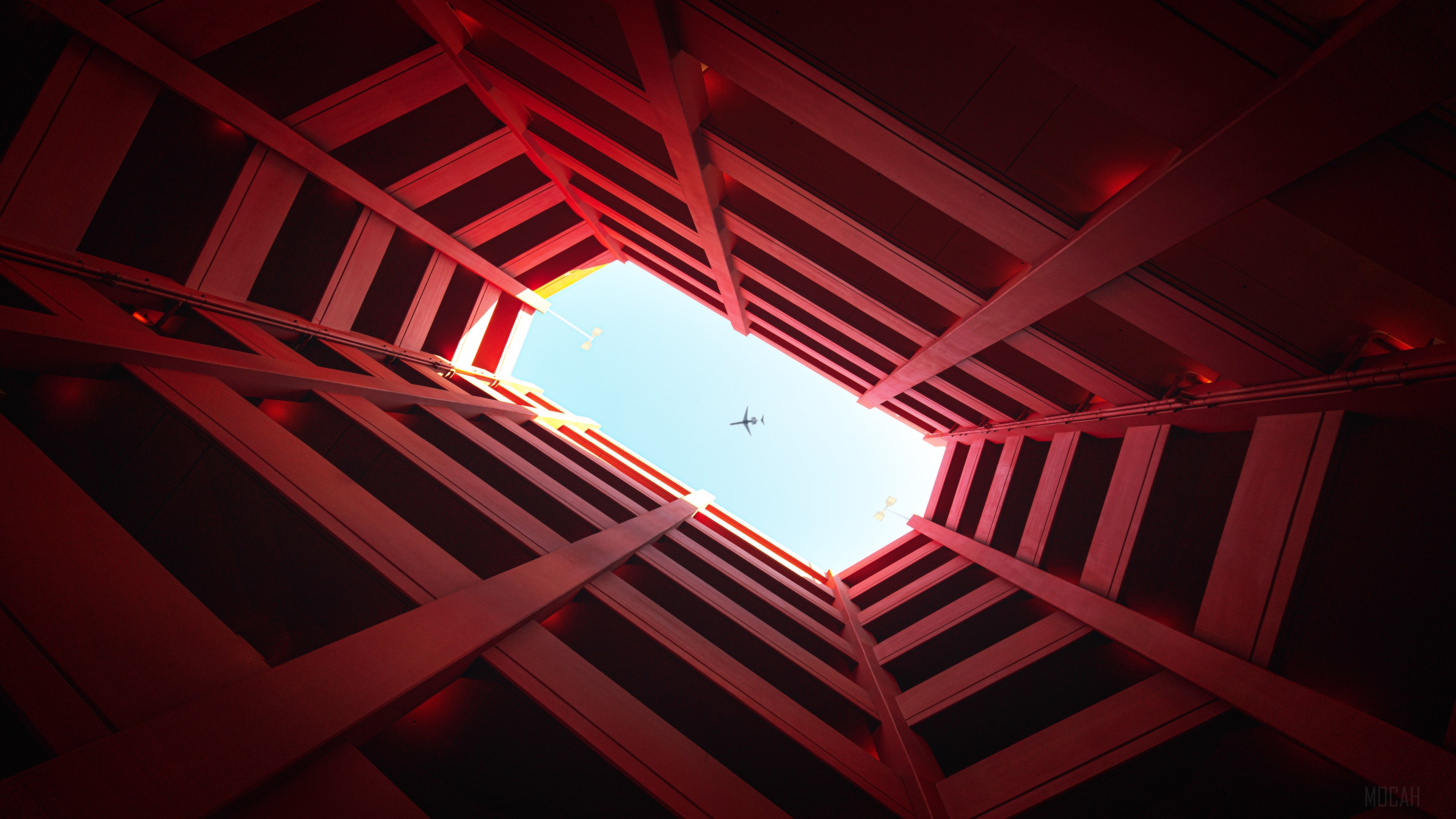Airplane flying through red architectural building 4K HD Wallpaper