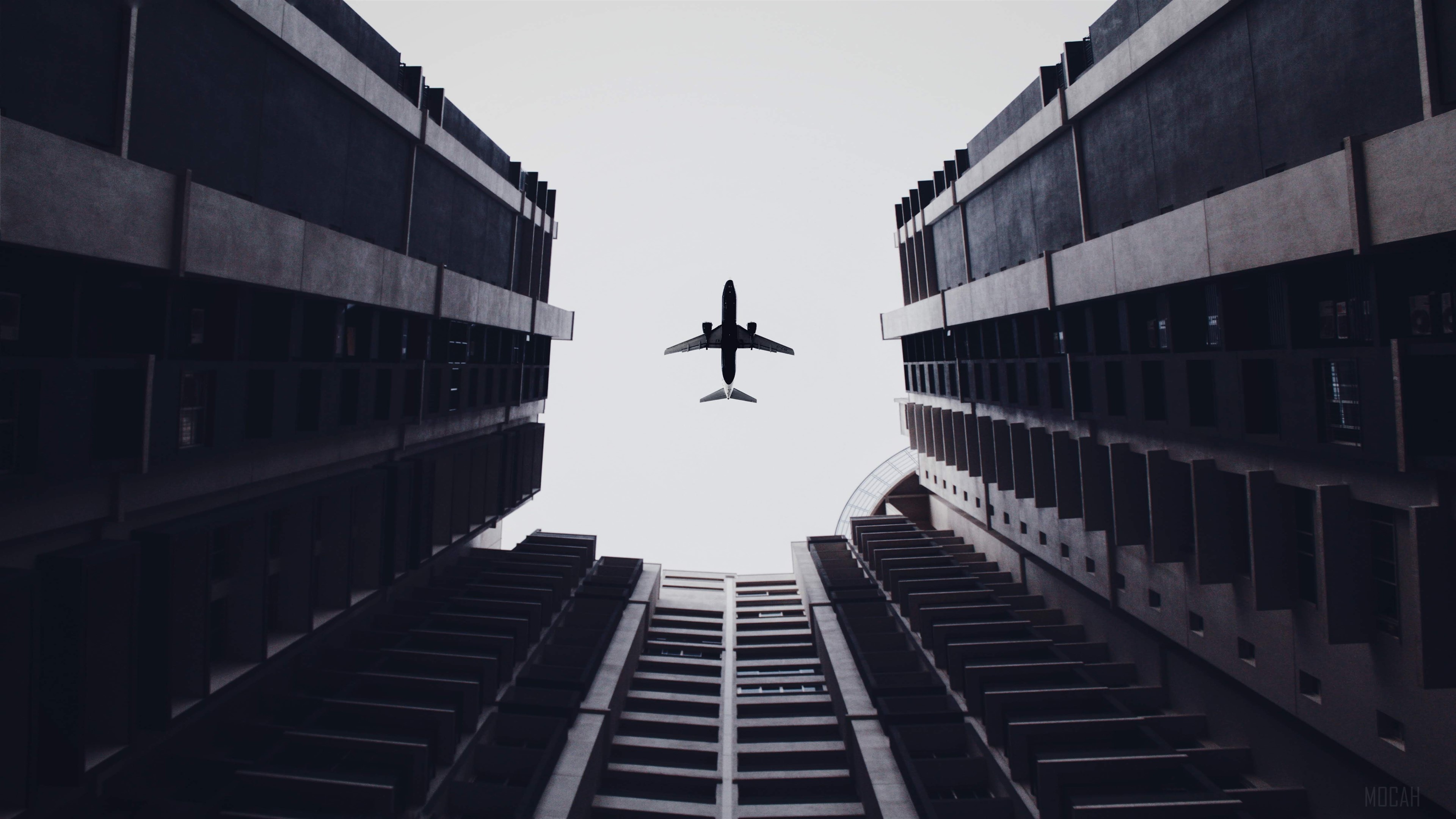 Airplane flying between buildings 4K HD Wallpaper