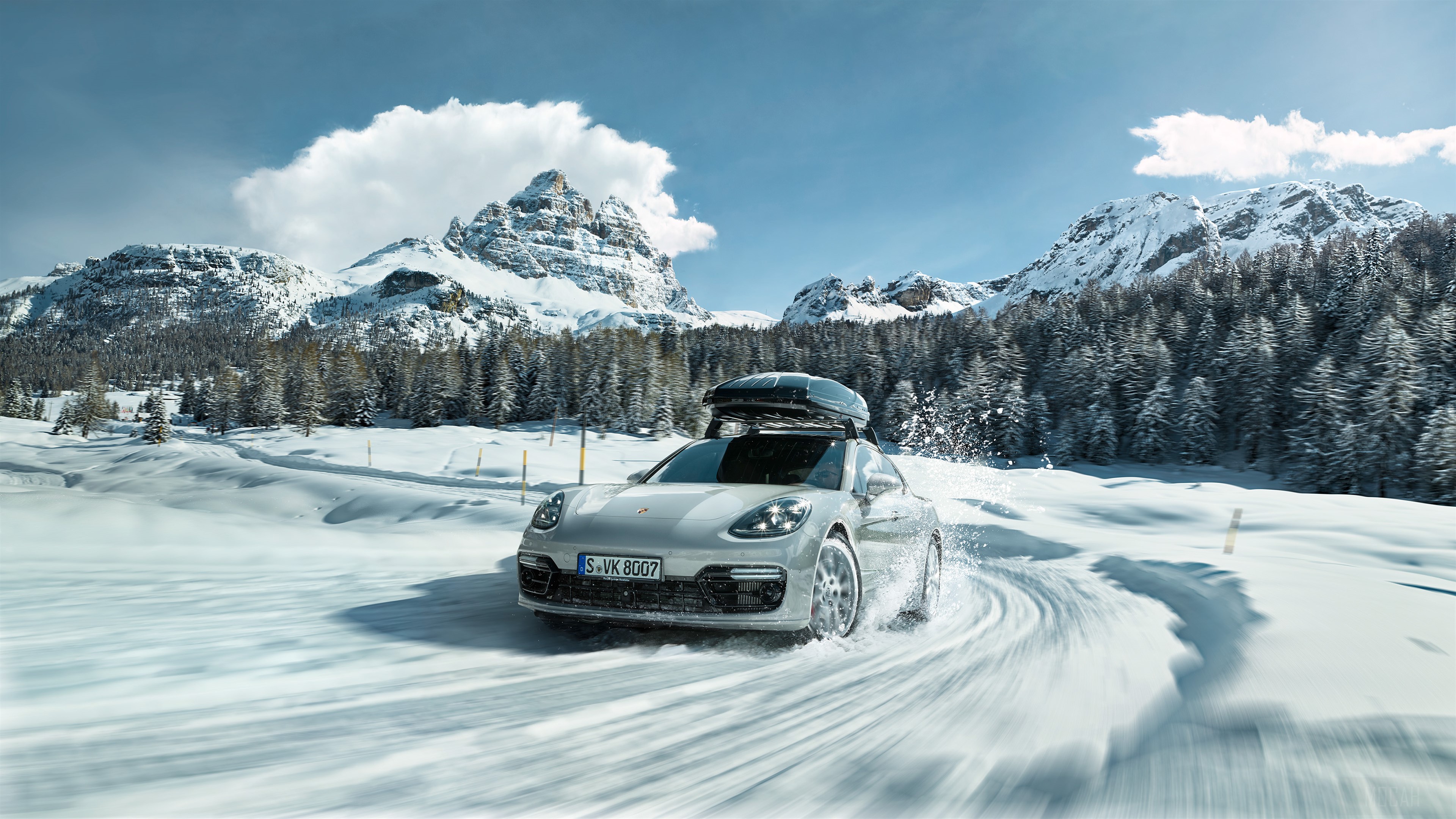 Porsche driving on a snowy mountain road HD Wallpaper