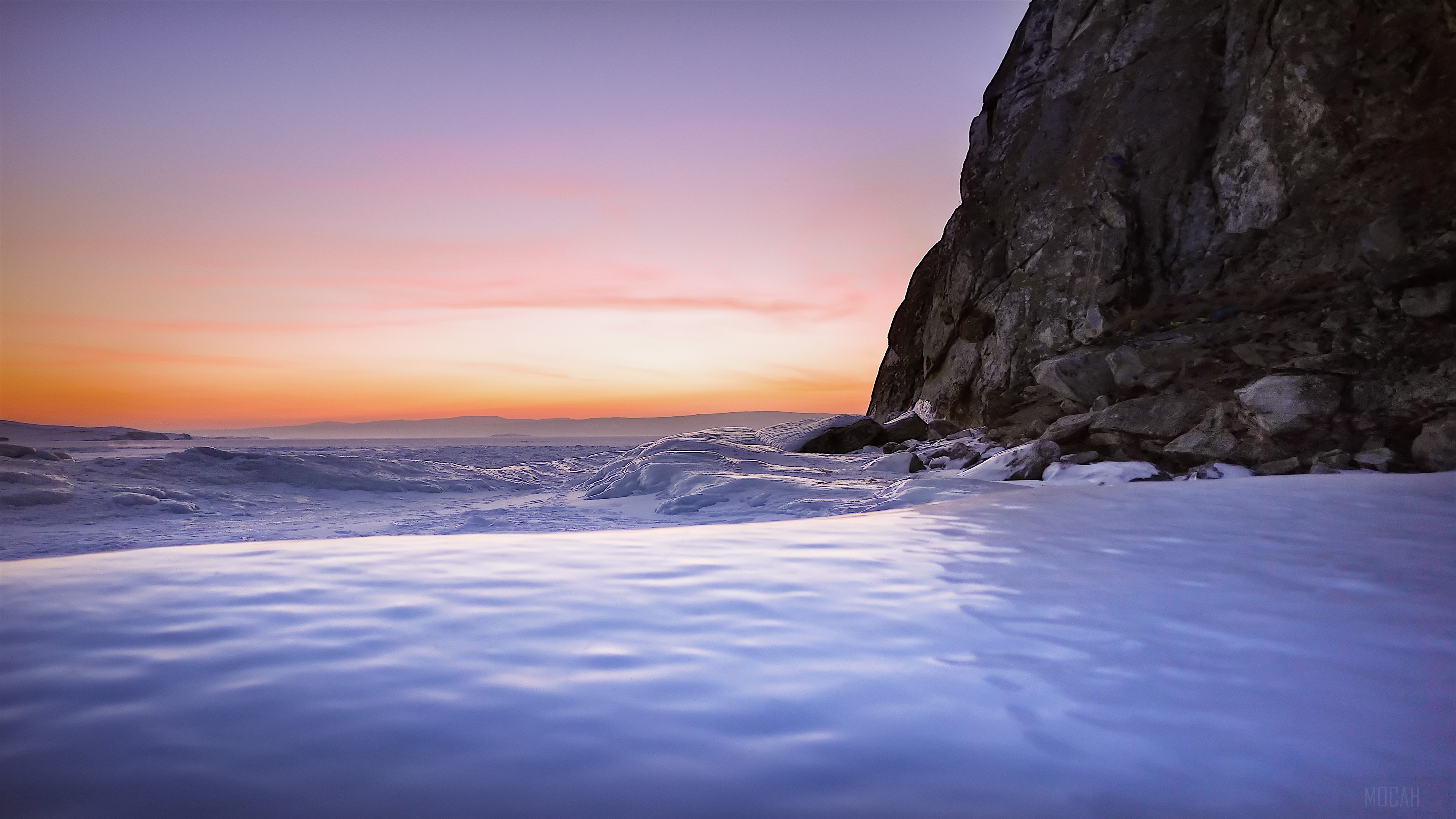 Frozen Sea Shore with Rocky Cliff at Sunset 4K HD Wallpaper