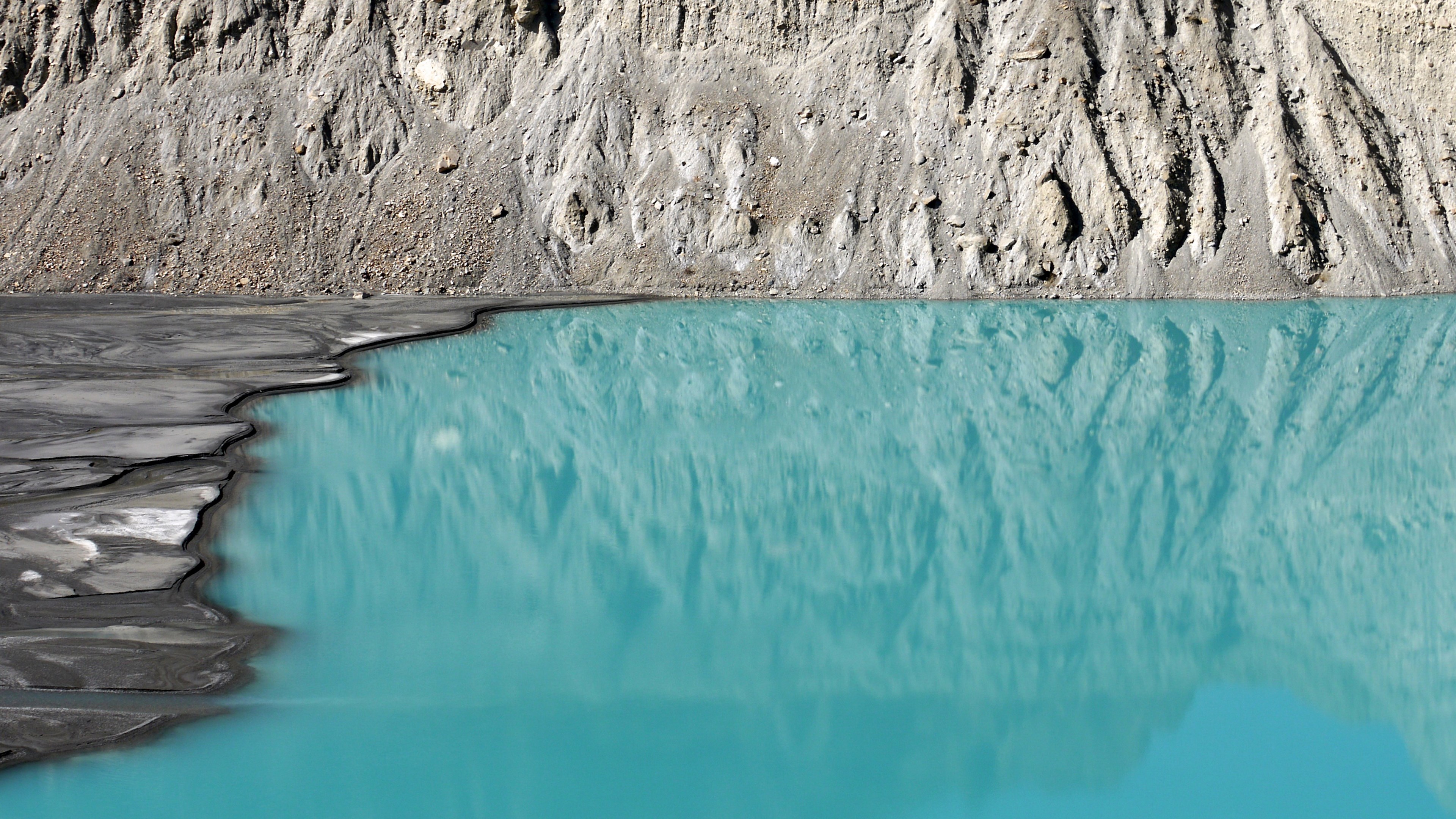 Turquoise glacial lake with rocky shore and reflection HD Wallpaper