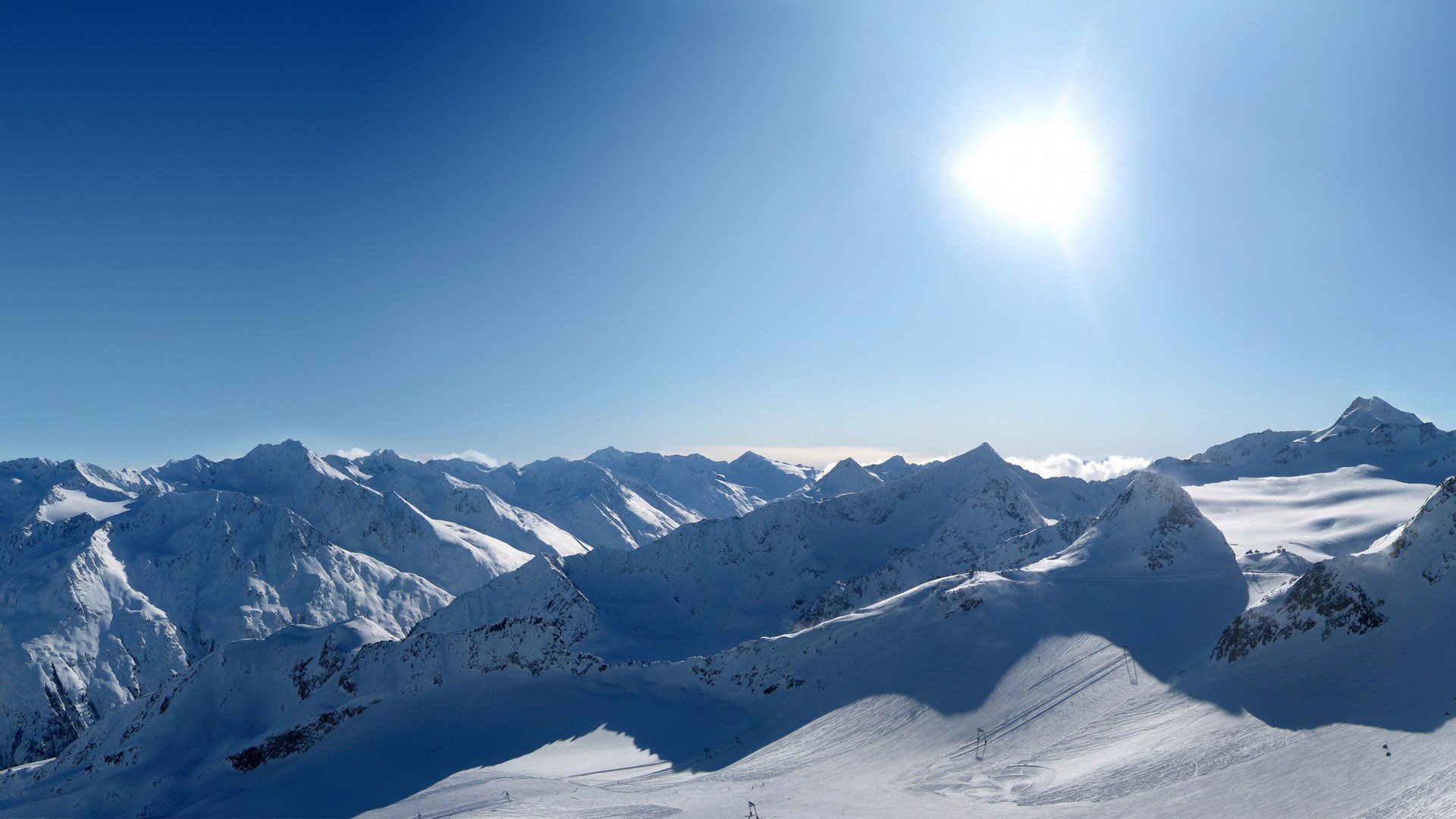 Snowy mountain range under a bright sun HD Wallpaper