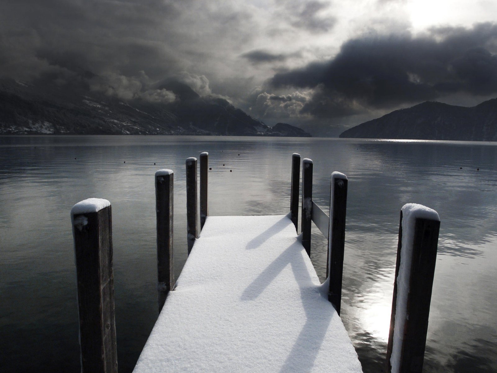 Snowy dock on a lake with mountains and stormy clouds HD Wallpaper