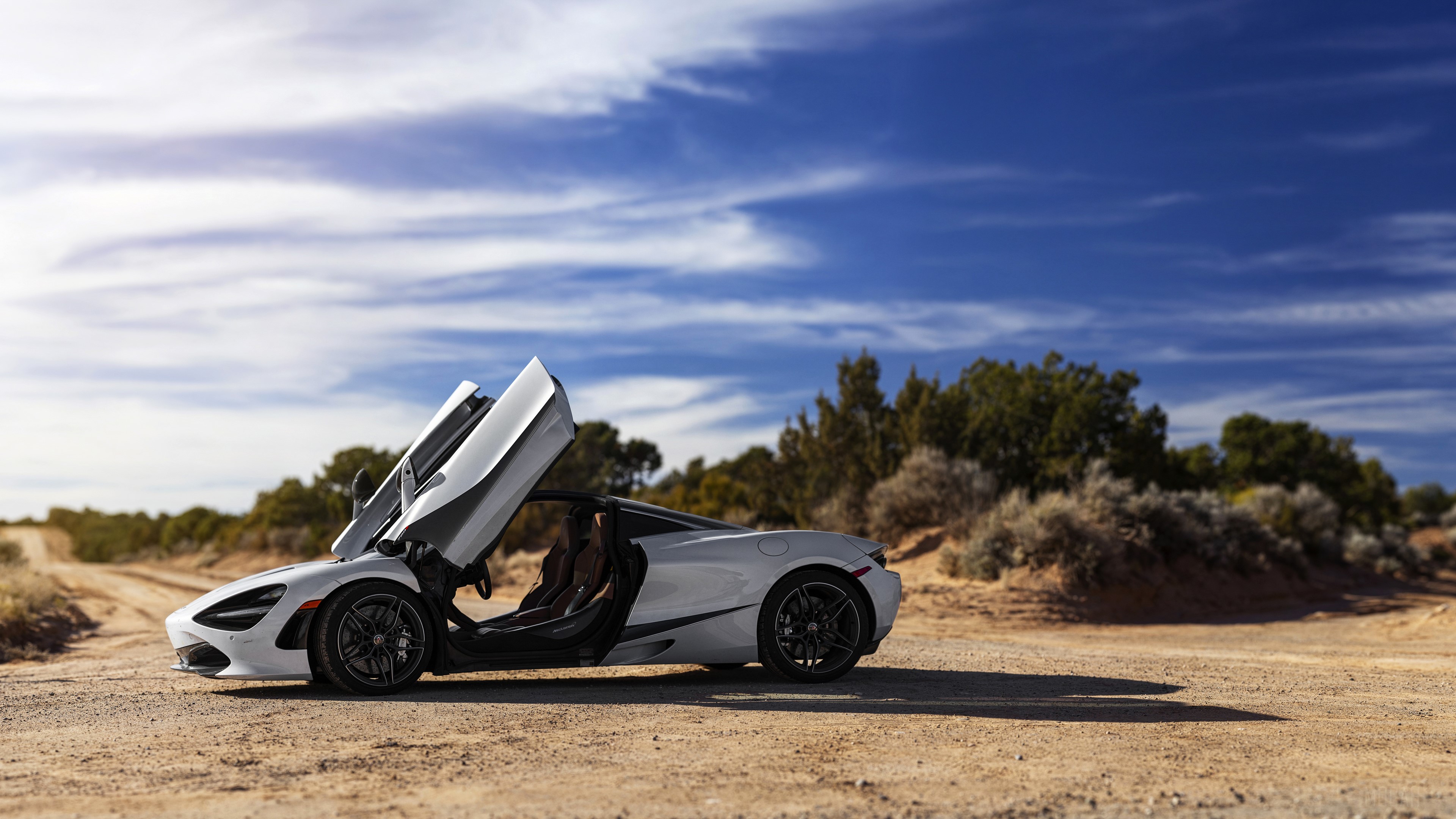 White McLaren 720S Coupe with doors open on dirt road HD Wallpaper