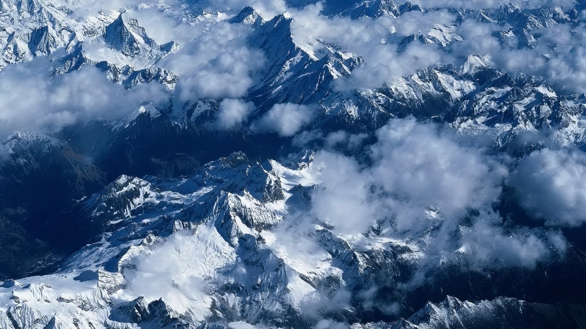Aerial view of snow-covered mountains and clouds HD Wallpaper