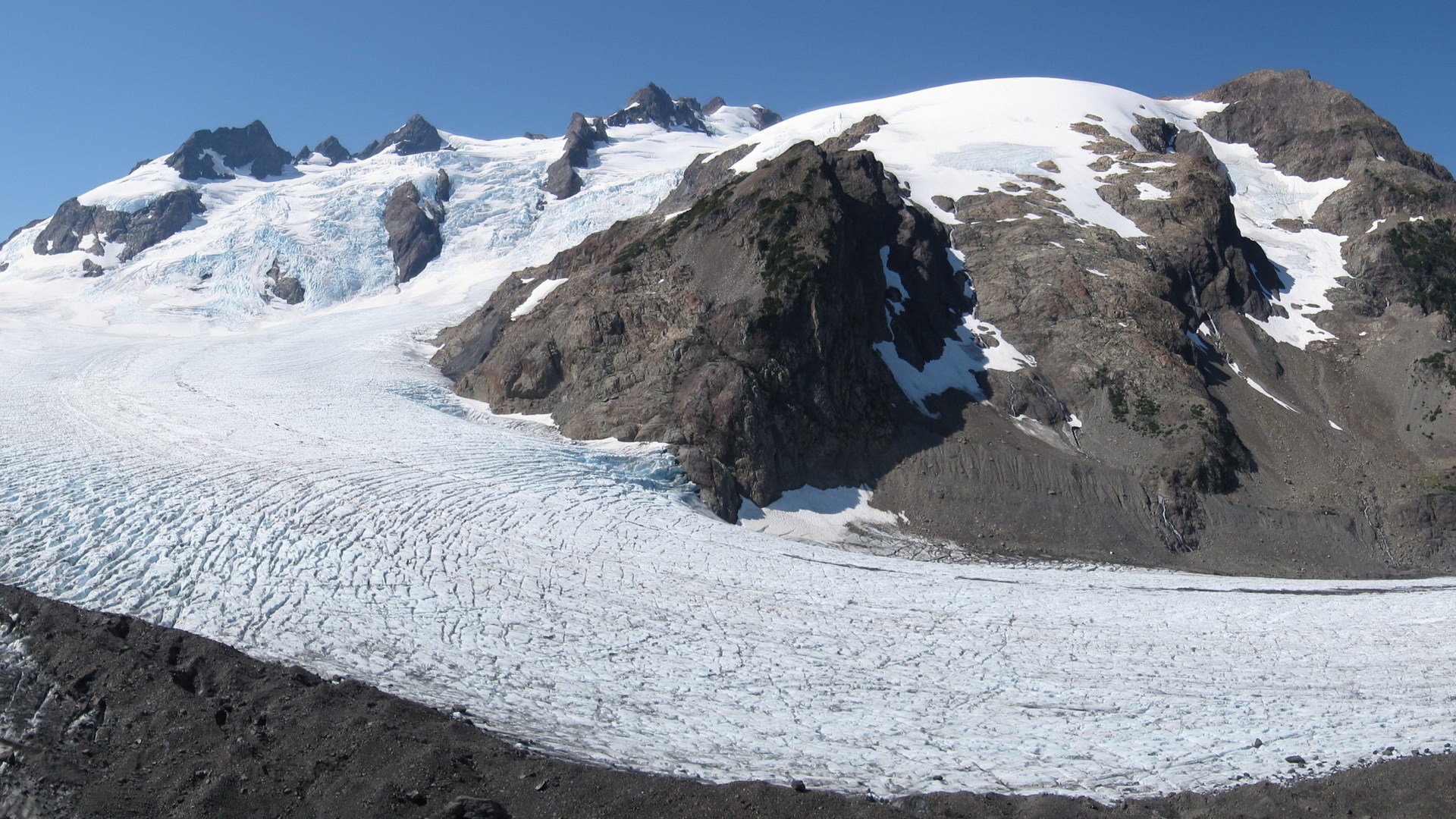 Glacier on a mountain range under a clear blue sky HD Wallpaper