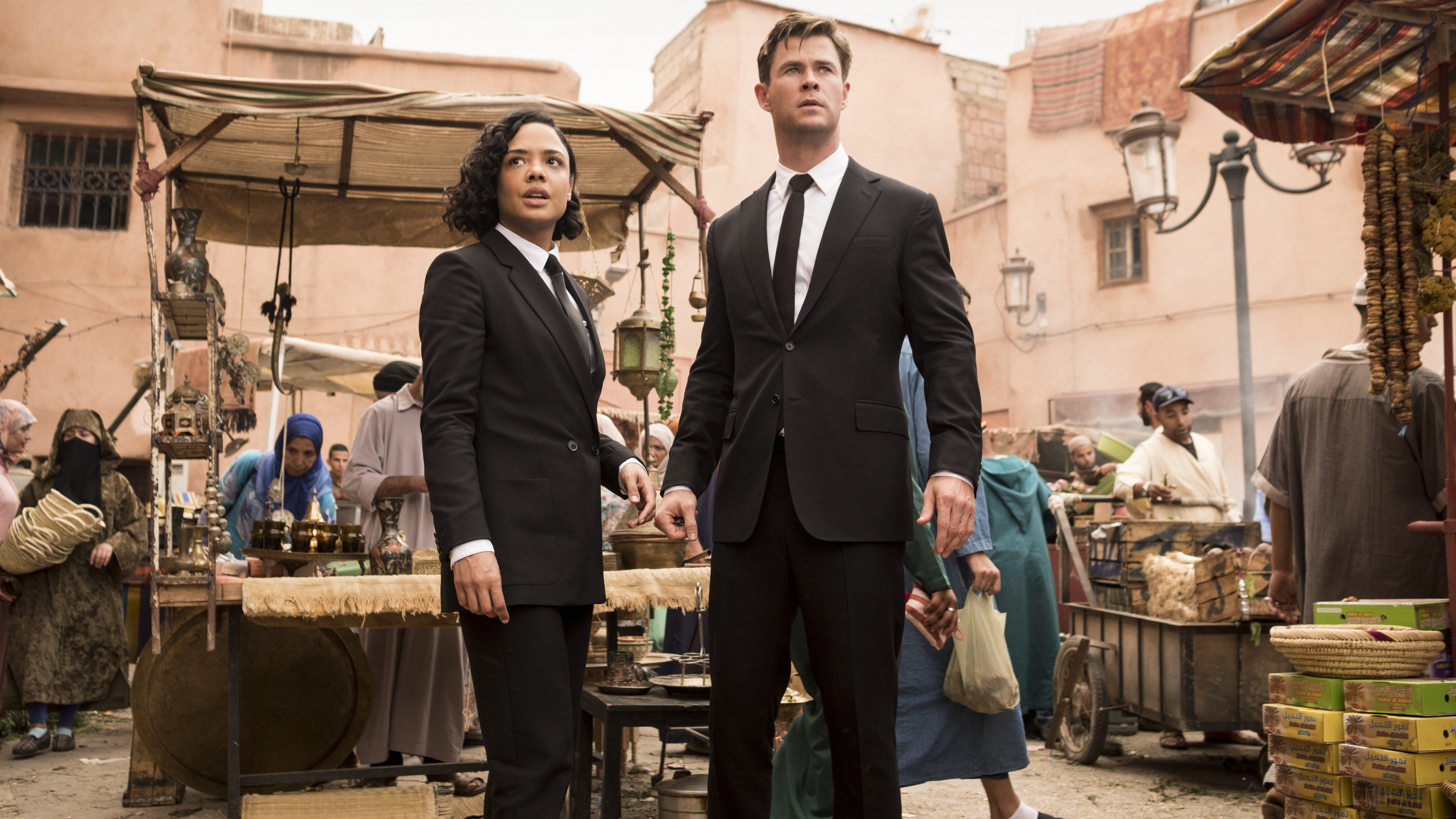 Agents from Men in Black International in a marketplace HD Wallpaper