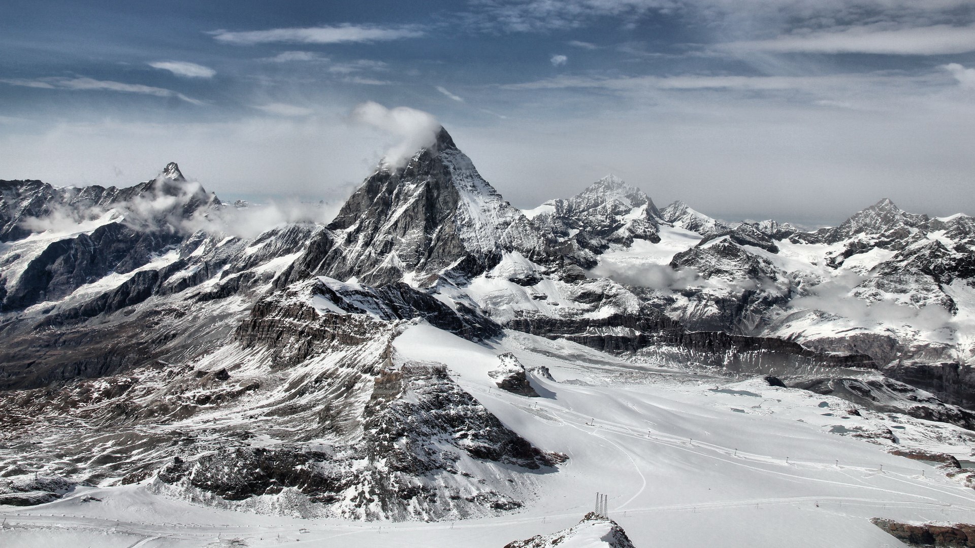 Snow-covered Matterhorn mountain range under a cloudy sky HD Wallpaper
