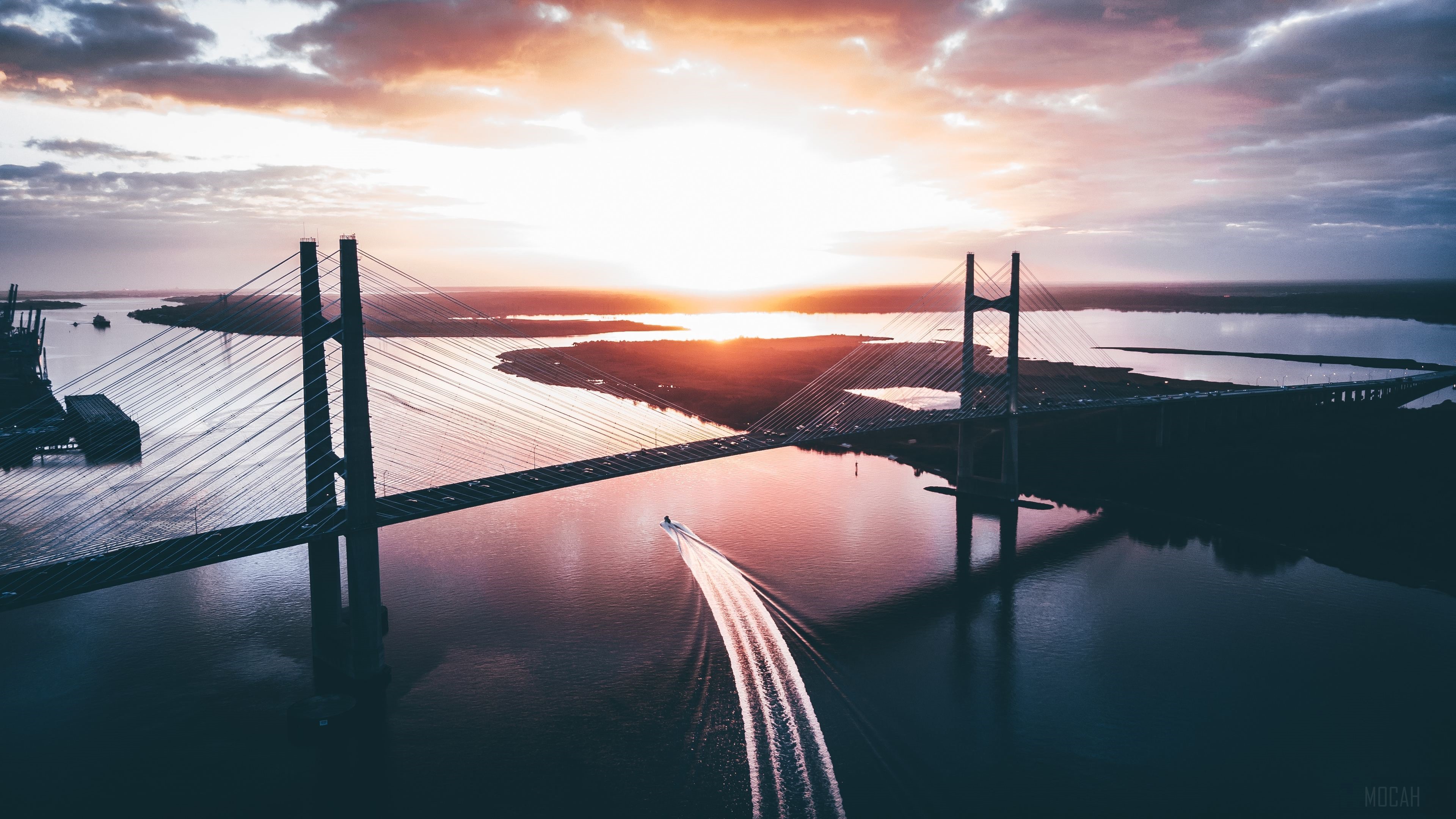 Cable-stayed bridge over river at sunset with boat HD Wallpaper