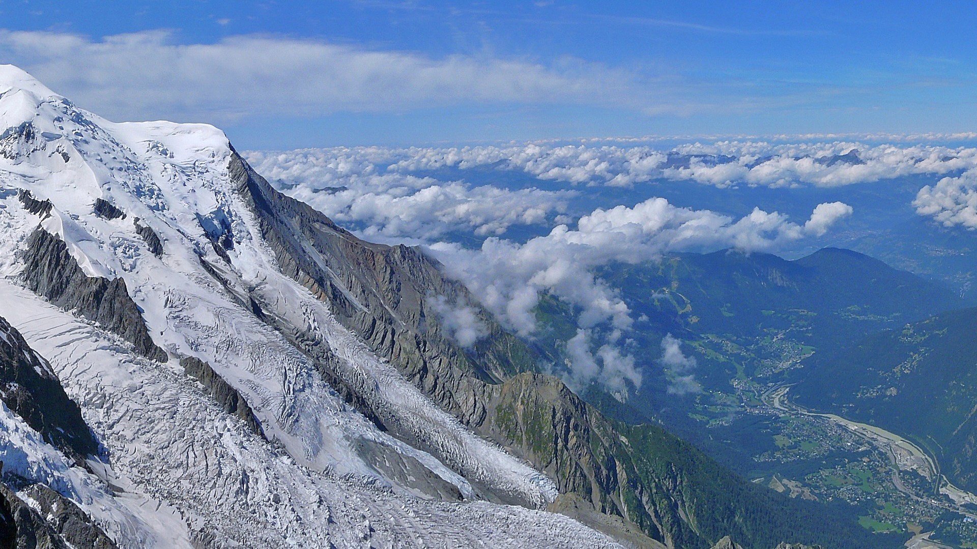 Snow-covered mountain peak above clouds and valley HD Wallpaper