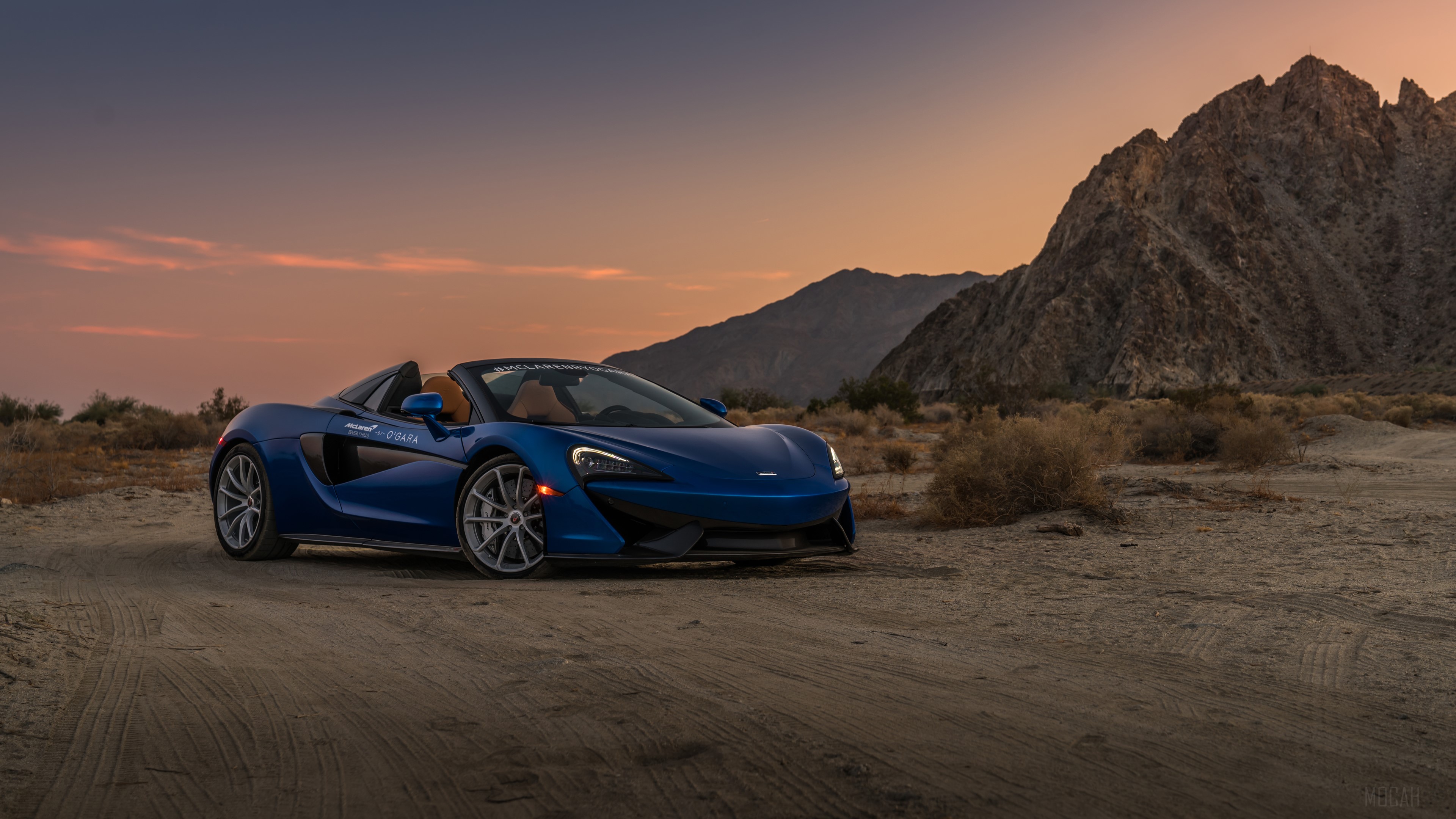 Blue McLaren convertible in desert landscape at sunset 4K HD Wallpaper