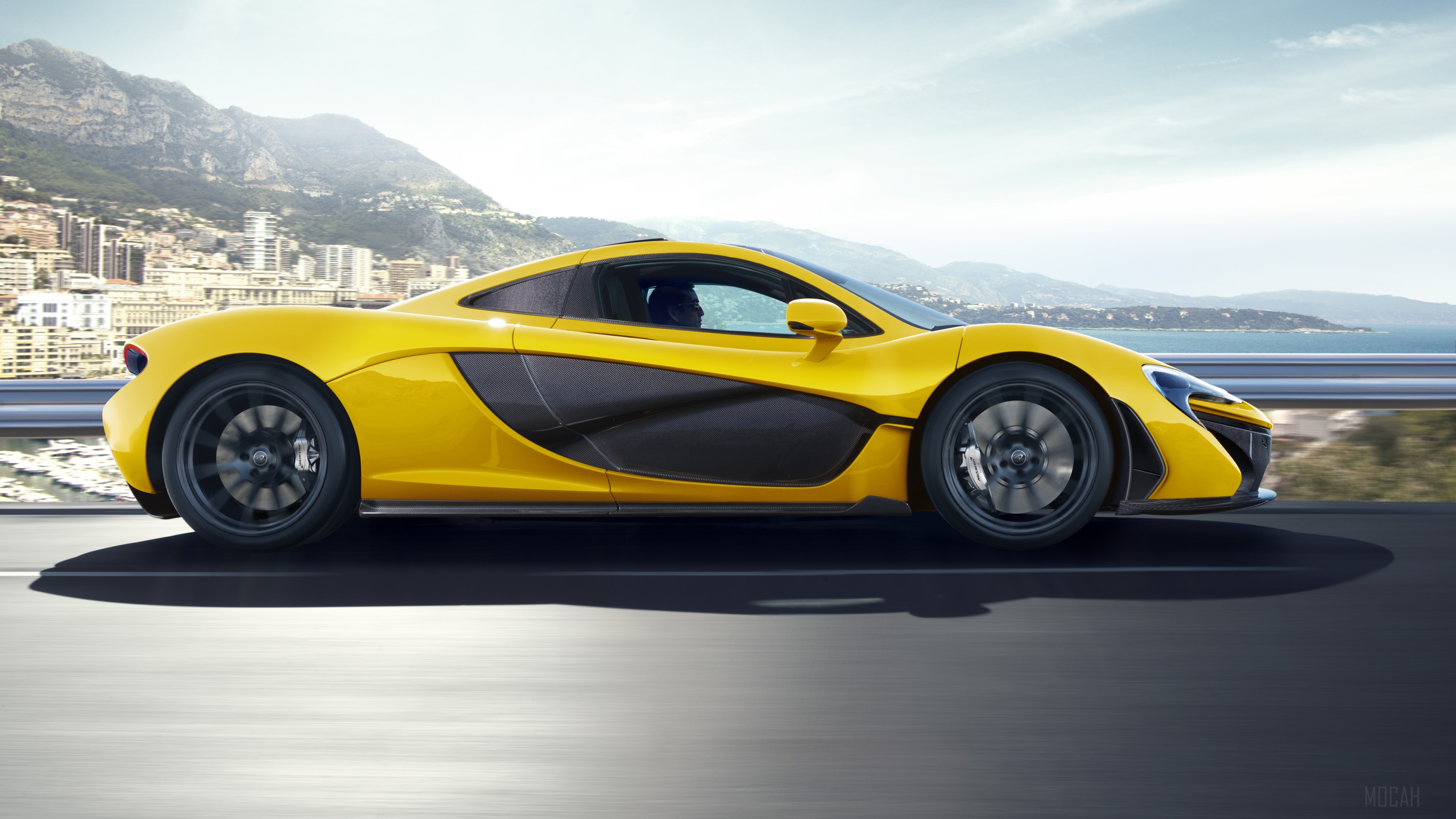 Yellow McLaren P1 driving on a coastal road HD Wallpaper