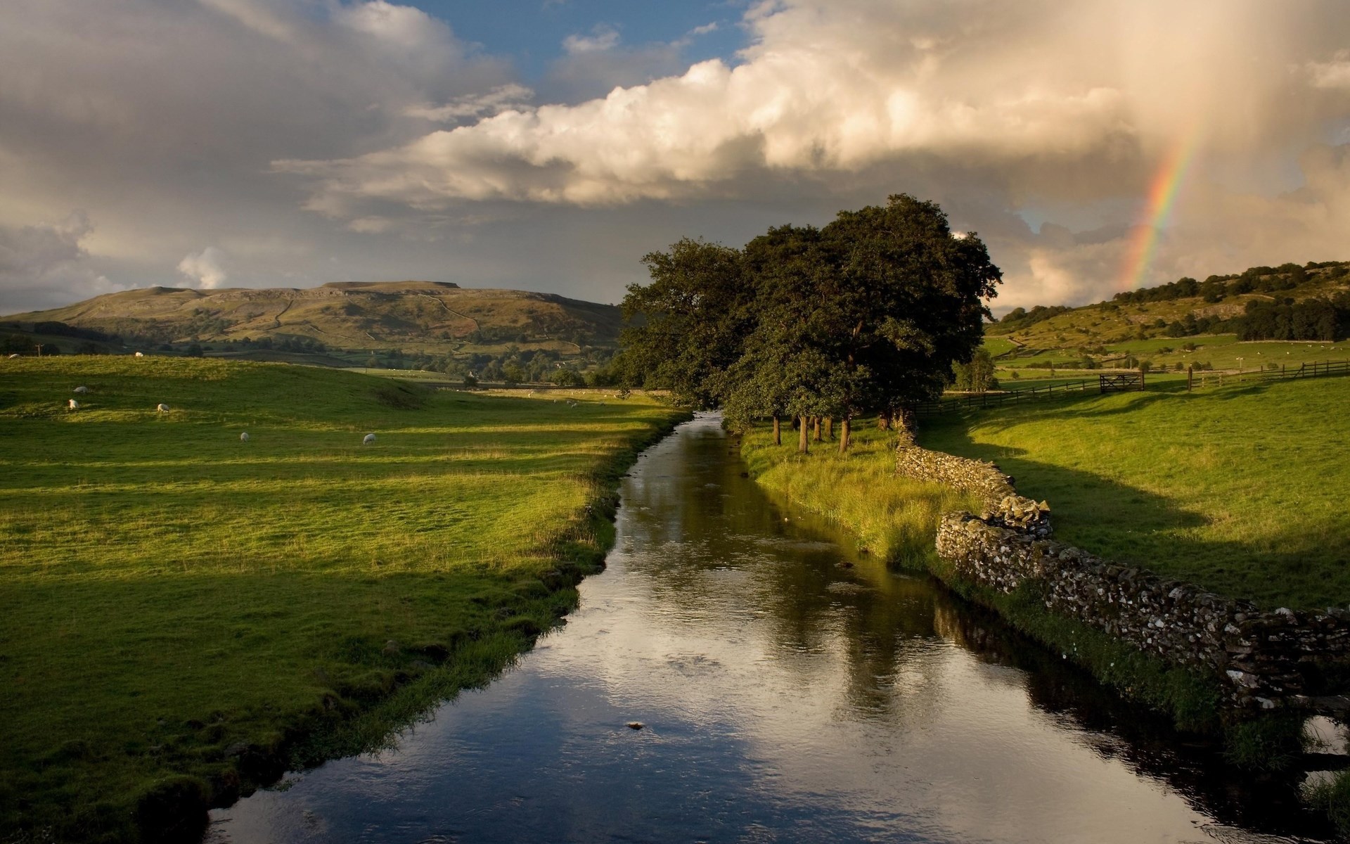 River flowing through green fields with a rainbow HD Wallpaper