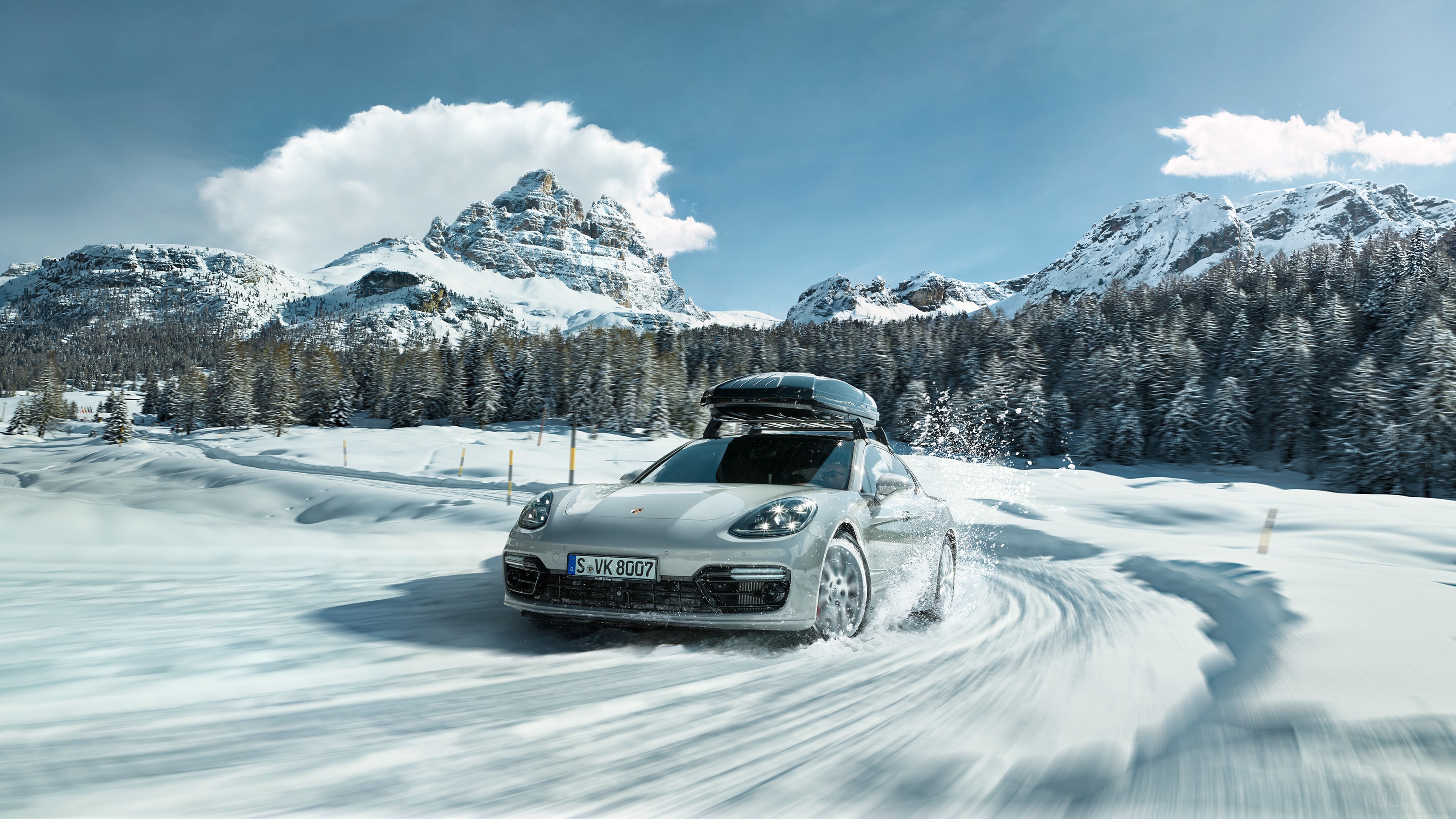 Porsche driving on a snowy mountain road HD Wallpaper