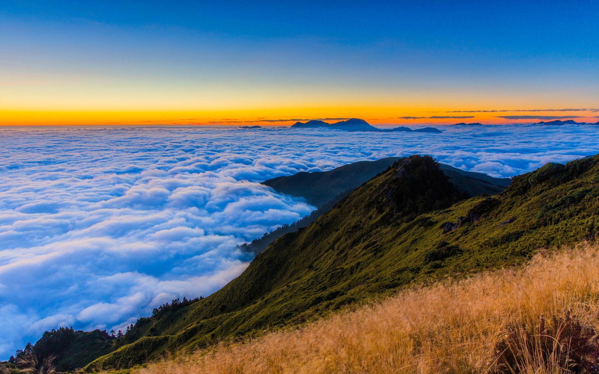 Mountain peaks above a sea of clouds at sunrise HD Wallpaper